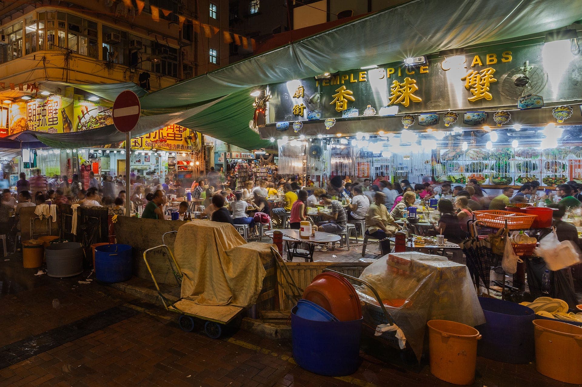 Atmospheric view of Temple Street Night Market in Hong Kong, with people dining, shopping and strolling.