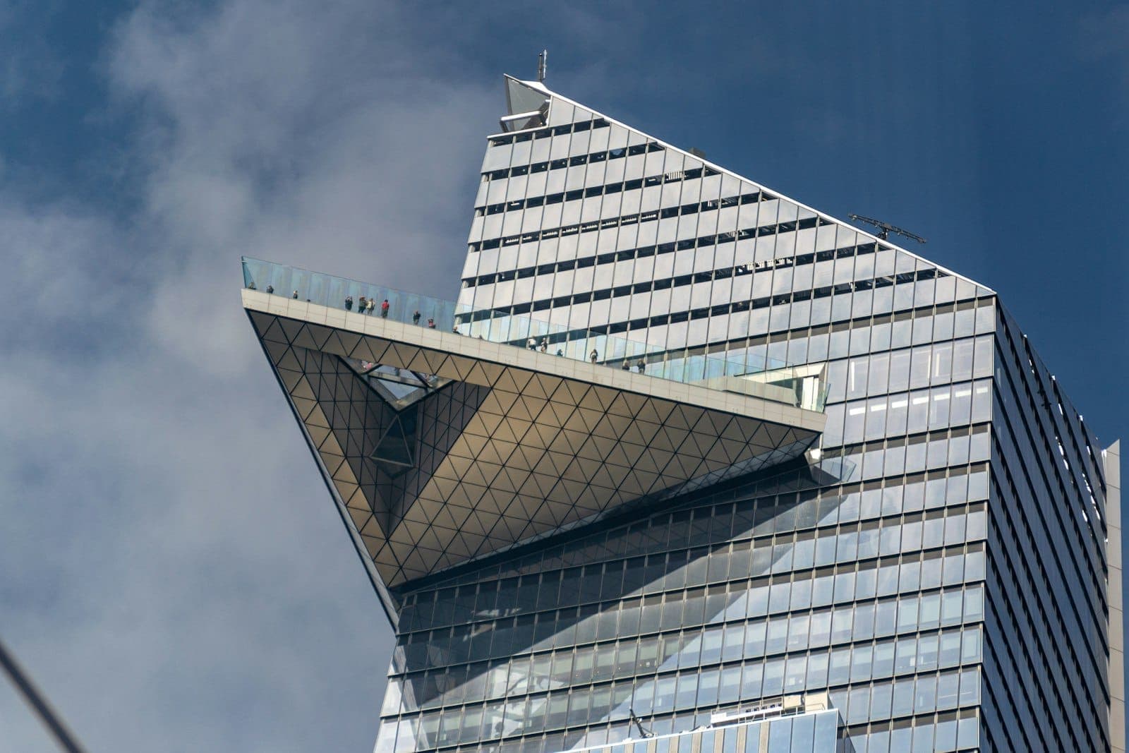 มุมใกล้ของดาดฟ้ากลางแจ้งรูปสามเหลี่ยม Edge NYC ที่ยื่นออกมาจากตึก 30 Hudson Yards ตัดกับท้องฟ้าสีฟ้า โชว์สถาปัตยกรรมสุดล้ำ