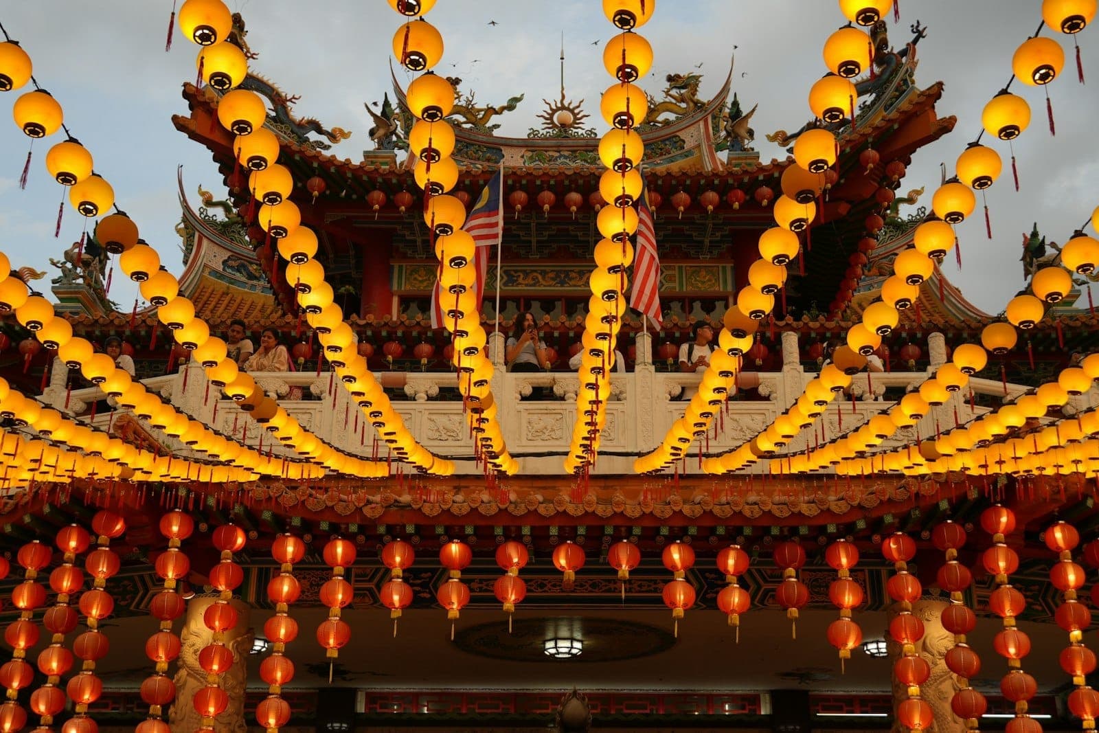 Kuala Lumpur'da kırmızı sütunları, süslü çatıları ve tepe üzerinden şehir silüetinin panoramik manzarasıyla altı katlı **Thean Hou Tapınağı**.