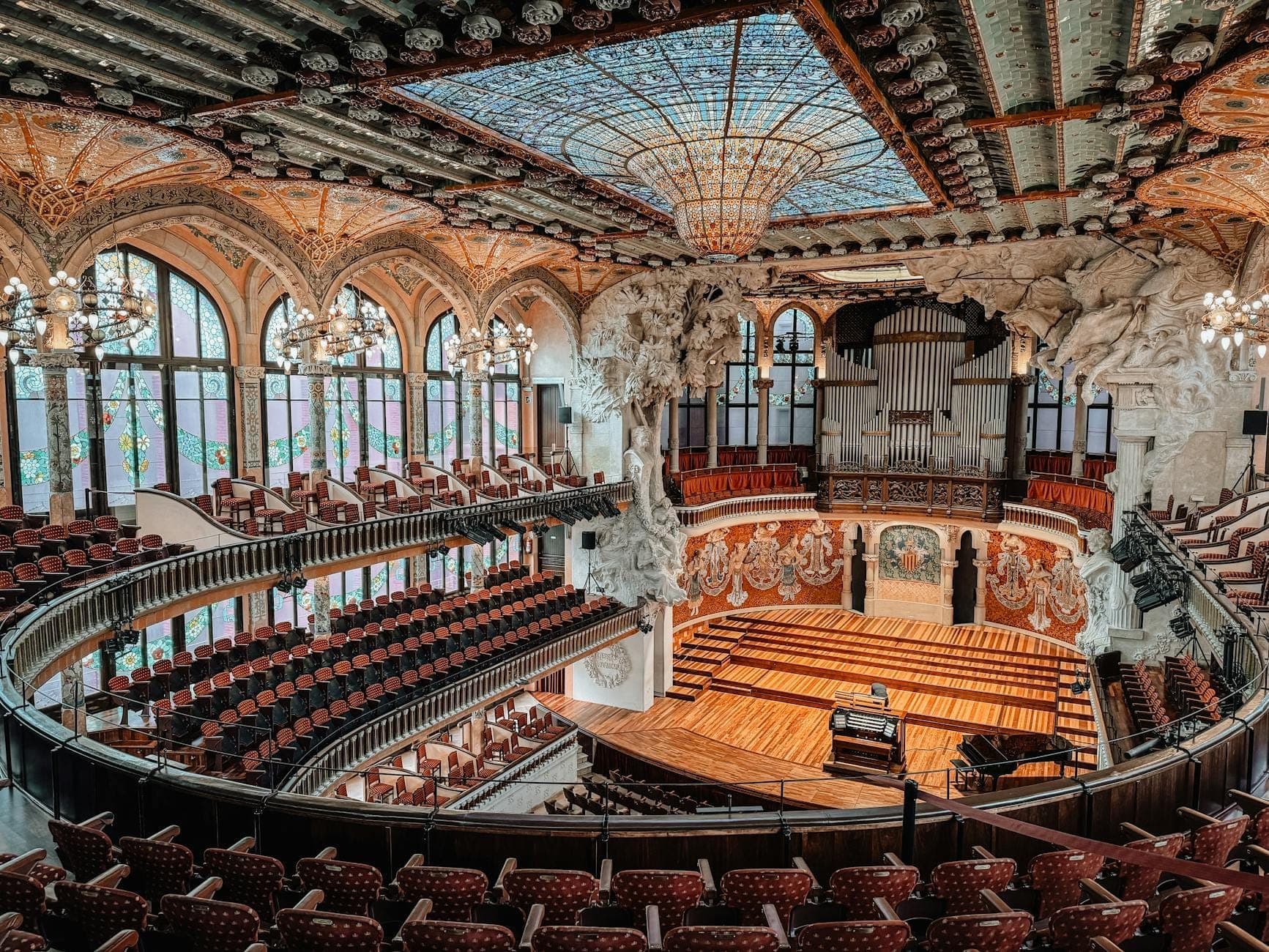 Vista grandangolare della sontuosa sala concerti del Palau de la Música Catalana con soffitto in vetrate, canne dell'organo ed eleganti balconi a Barcellona.