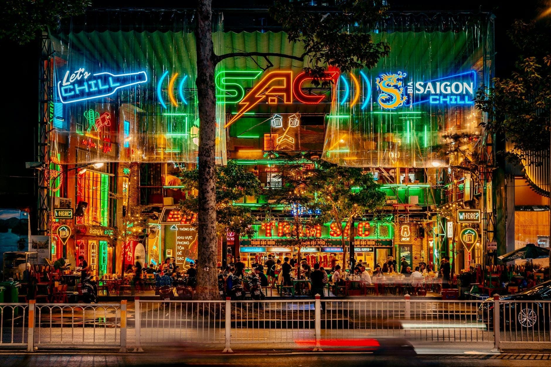 Isang makulay at maingay na kalye sa Ho Chi Minh City na naiilawan ng makulay na mga neon sign at puno ng mga taong nag-eenjoy ng masayang atmosphere ng nightlife.