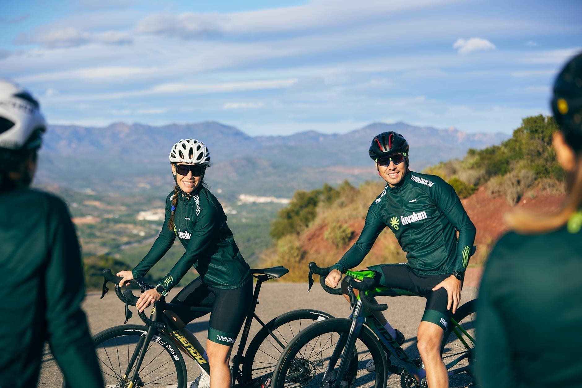 Ciclisti in abbigliamento professionale che percorrono una panoramica strada di montagna con le montagne Tramuntana di Mallorca sullo sfondo.