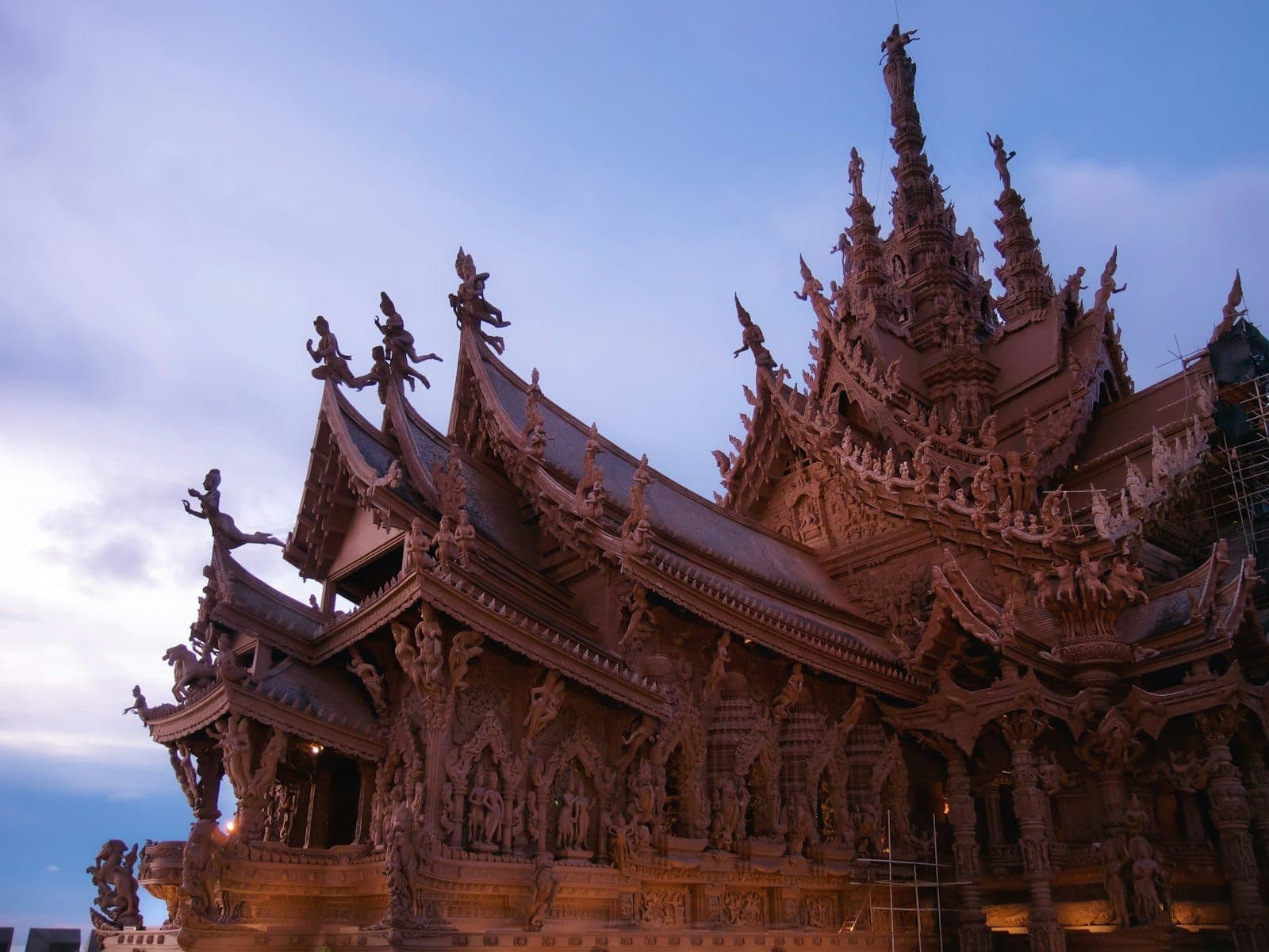 Широкоугольный вид на храм Sanctuary of Truth в Паттайе в сумерках с искусной деревянной резьбой и замысловатыми деталями крыши.