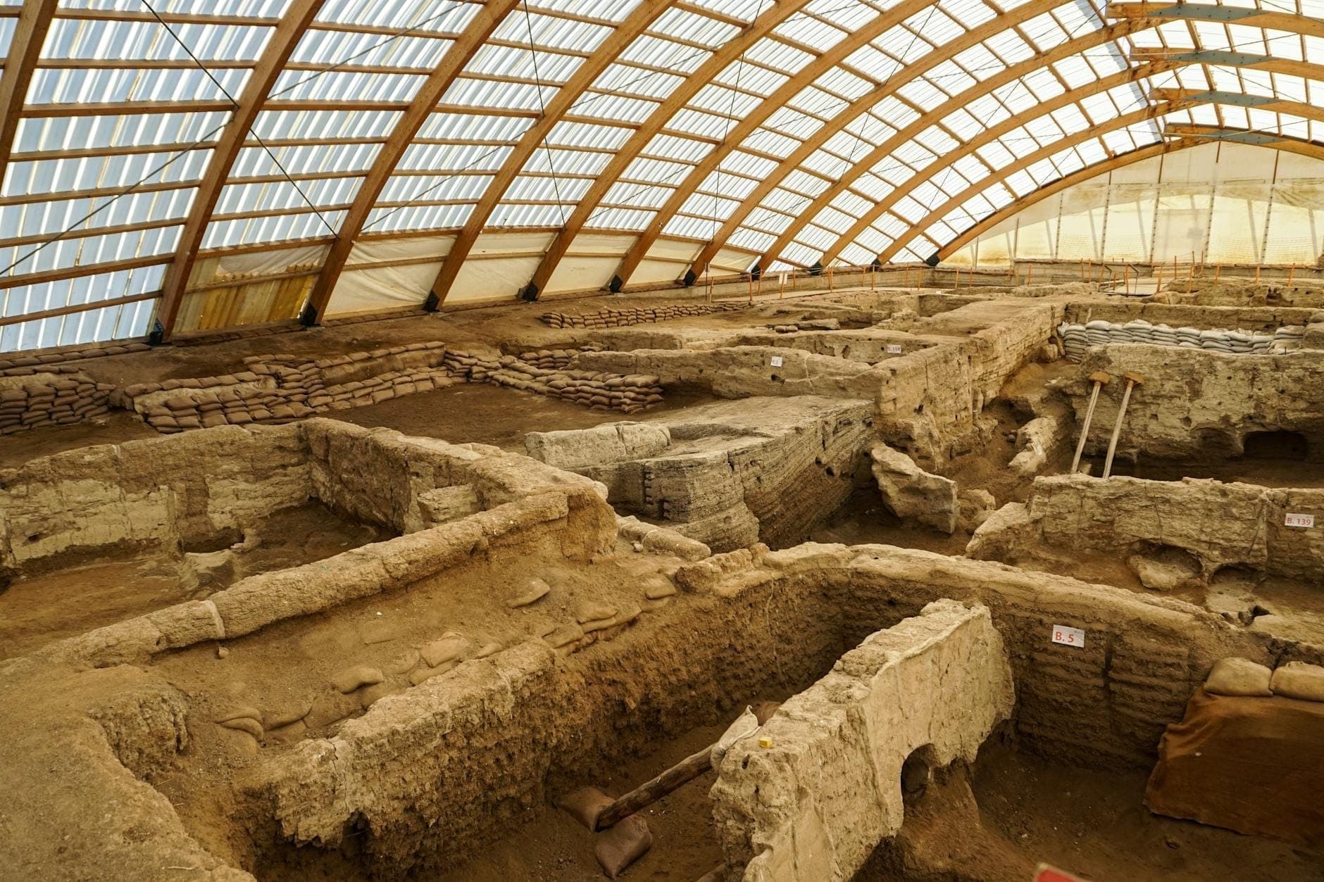 Vista interna del sito archeologico di Akrotiri a Santorini, con rovine antiche e aree di scavo sotto una copertura protettiva.