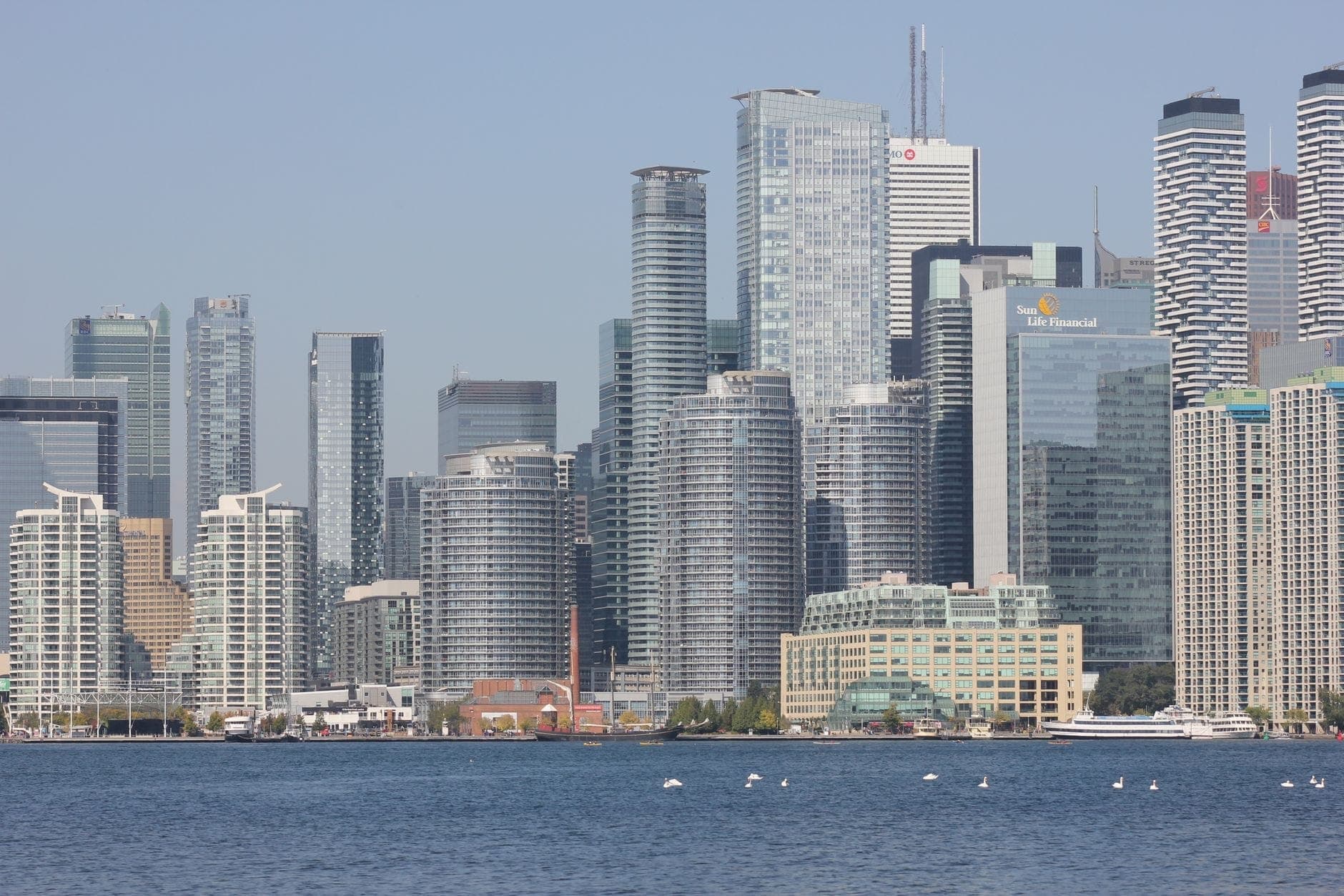 Toronto waterfront skyline with many modern glass condo towers rising above the lake on a clear day.