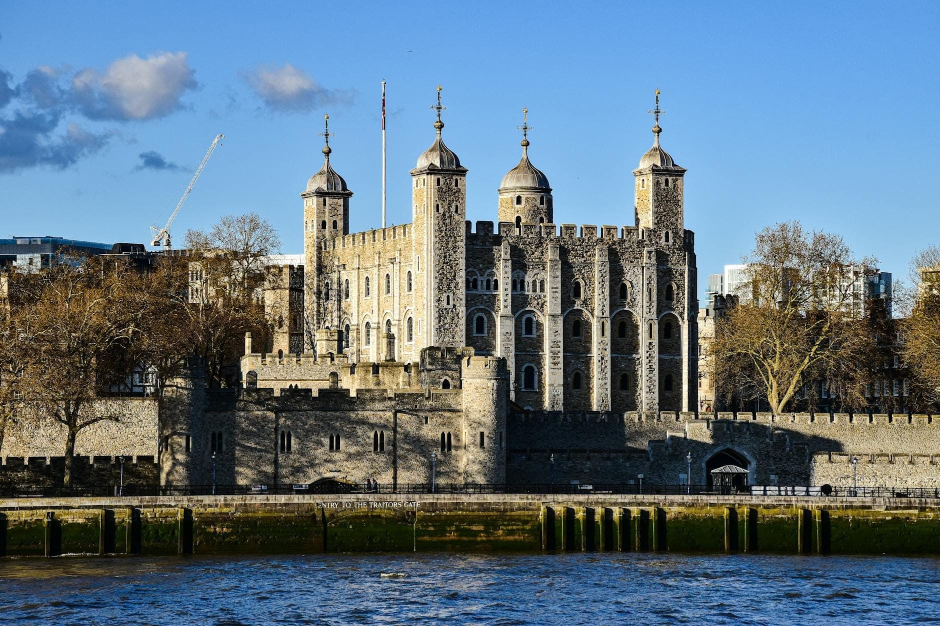 Tháp London nhìn từ bên kia sông Thames vào một ngày nắng đẹp với bầu trời xanh trong, toàn cảnh pháo đài cùng những tháp canh mang tính biểu tượng.