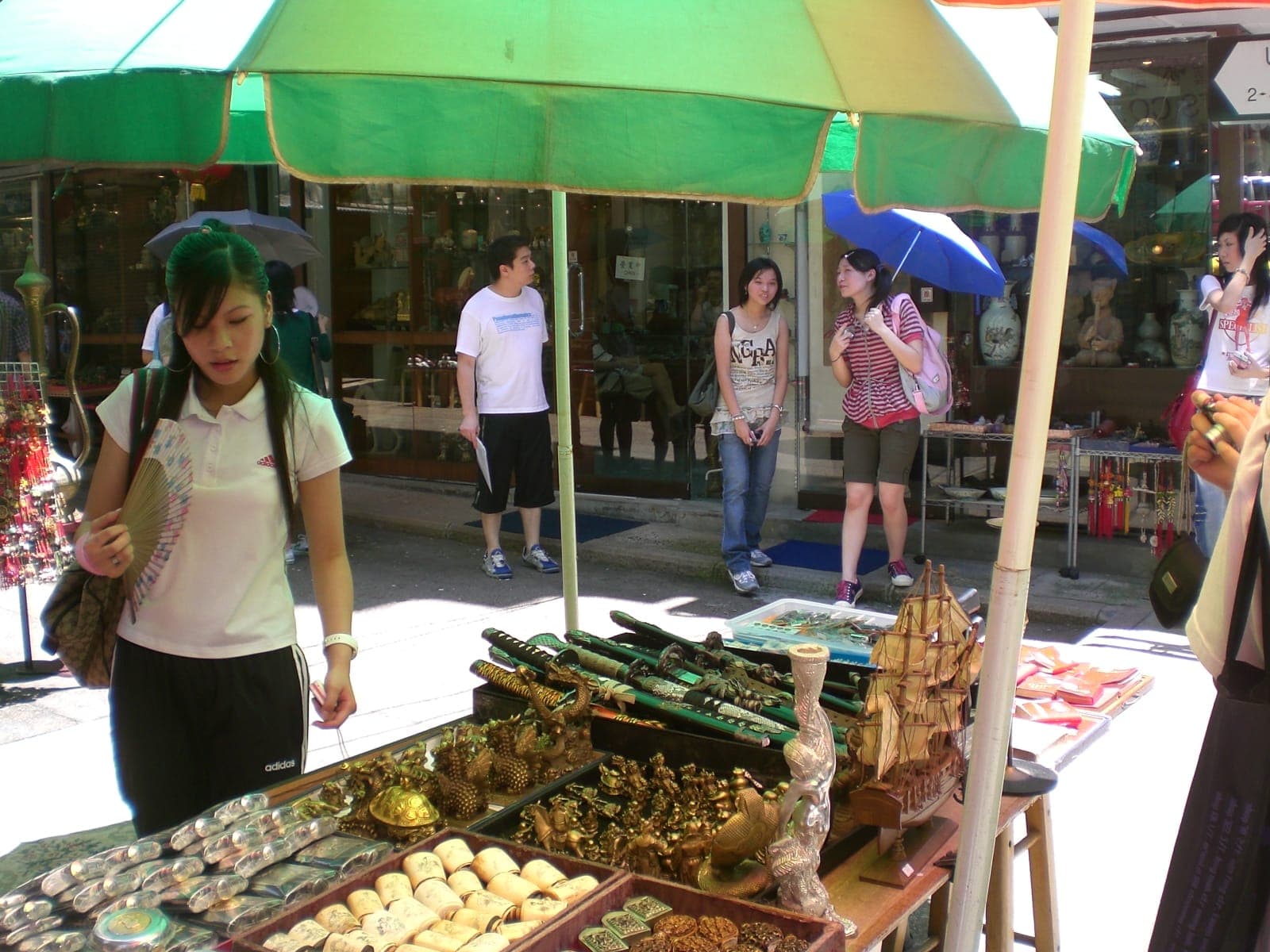 Bustling shops and stalls along Upper Lascar Row (Cat Street) in Hong Kong, displaying antiques and curios on vibrant market shelves.