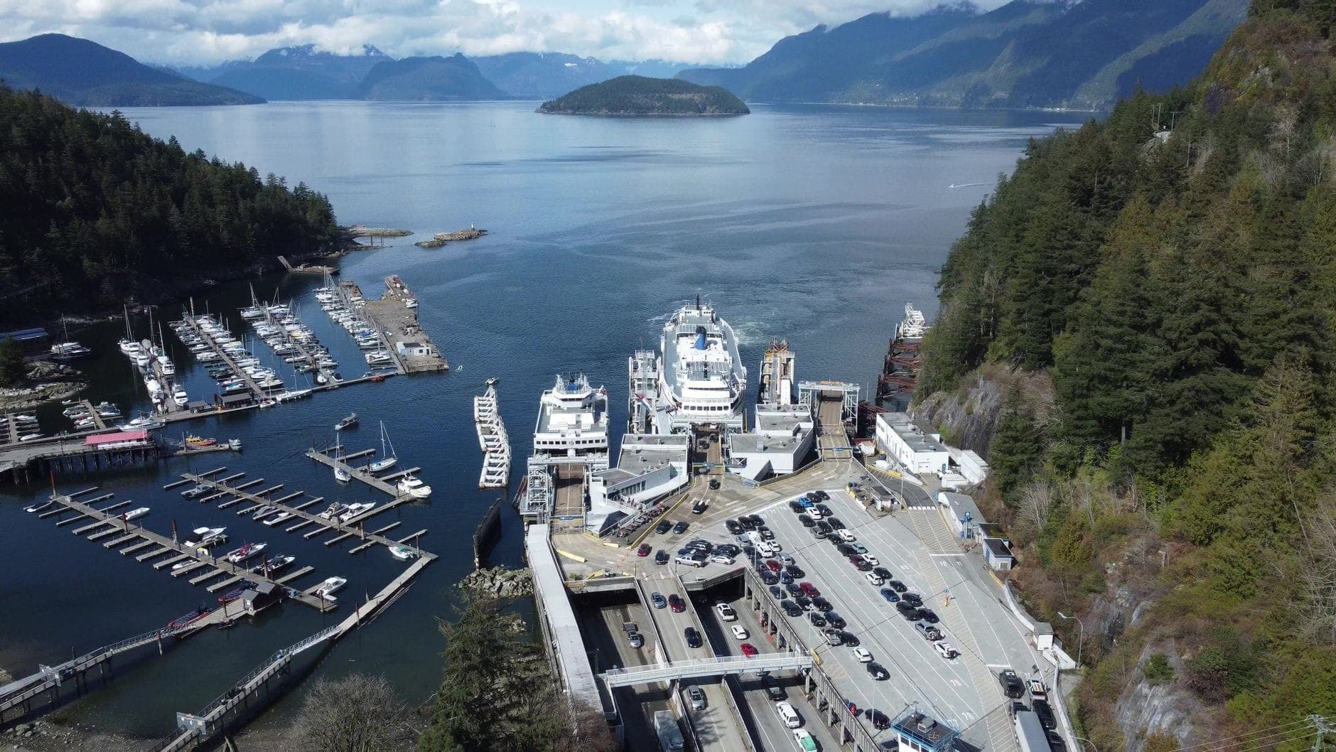 ภาพมุมสูงของท่าเรือ BC Ferries มีเรือจอดอยู่ รายล้อมด้วยมารีน่าและภูเขา มองเห็นน้ำสีสวยระหว่างแวนคูเวอร์กับเกาะแวนคูเวอร์