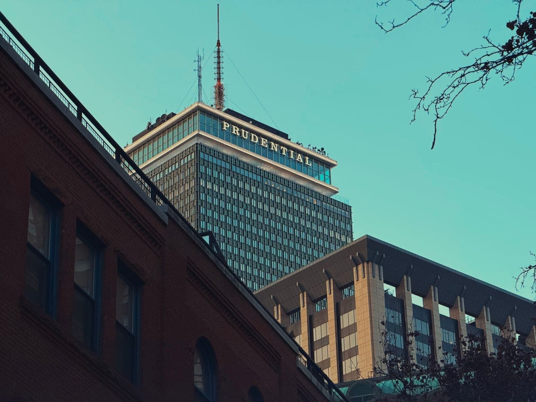 La Prudential Tower s'élève au-dessus des bâtiments voisins à Boston, ses derniers étages visibles sous un ciel bleu dégagé.
