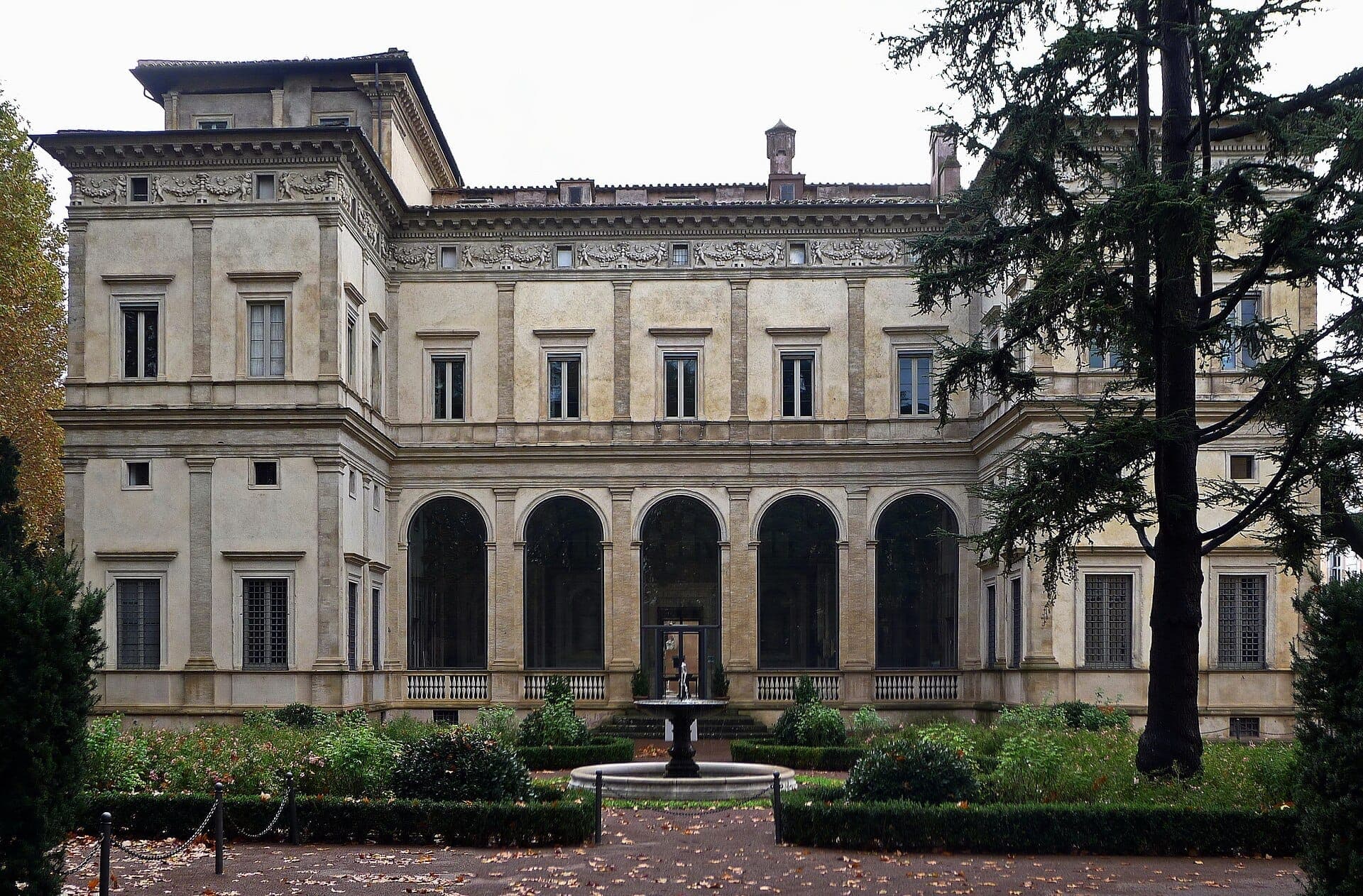 Harapang tingin ng Villa Farnesina sa Roma, na nagtatampok ng arkitekturang Renaissance, malalaking arko na bintana, maayos na hardin, at isang sentral na fountain sa ilalim ng maulap na langit.