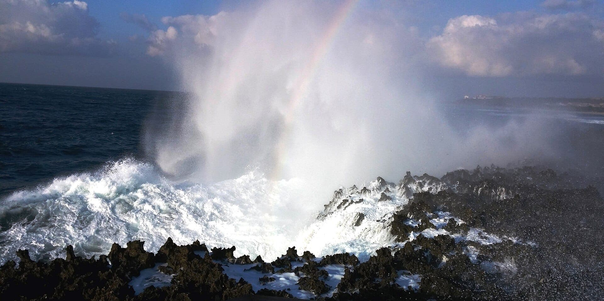 Powerful waves erupting through volcanic rocks at Waterblow Nusa Dua, Bali, sending seawater plumes high into the sky.