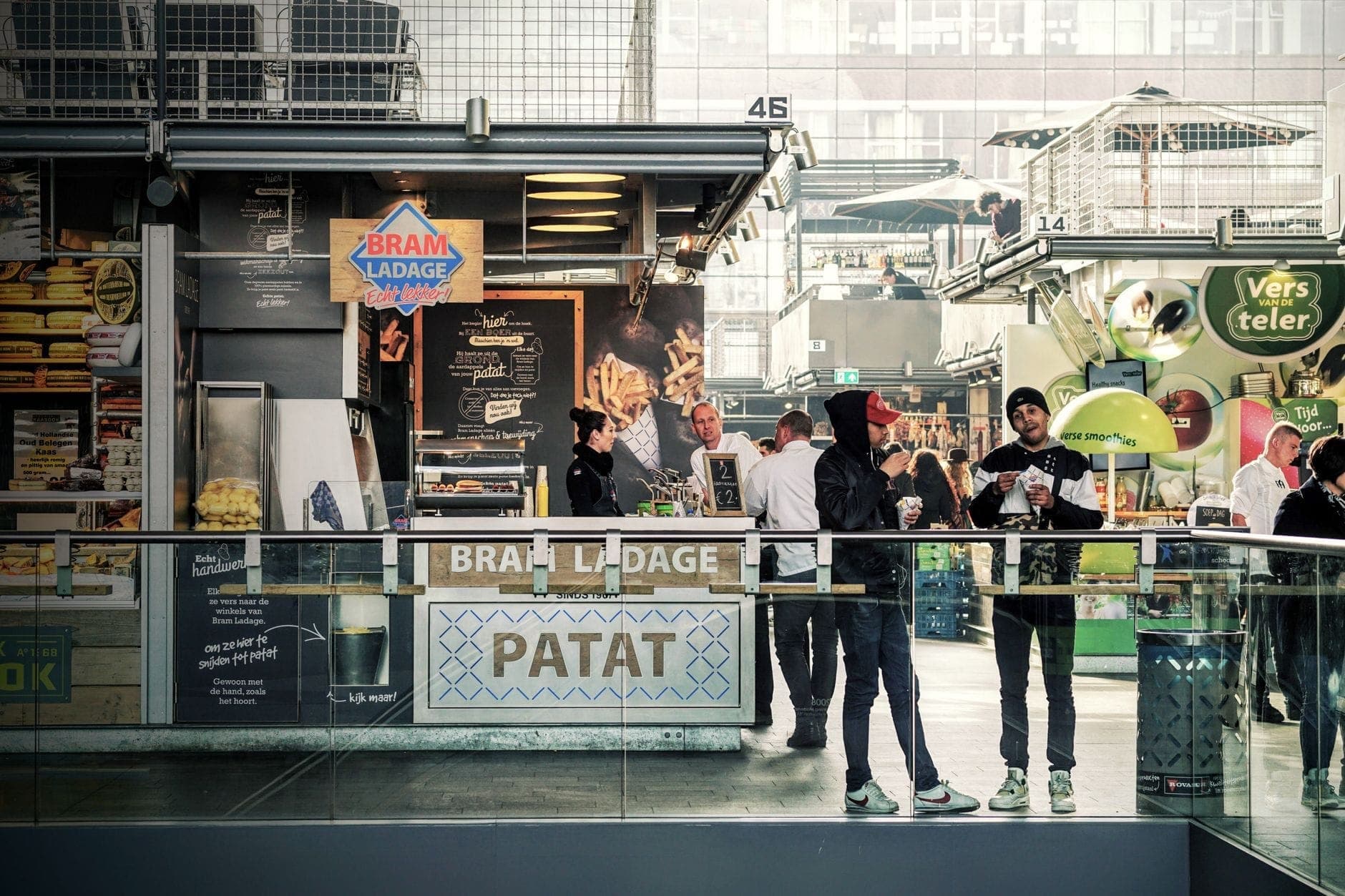 Interior de un animado mercado gastronómico cubierto con personas pidiendo en los puestos de comida y disfrutando de sus comidas en Berlín.