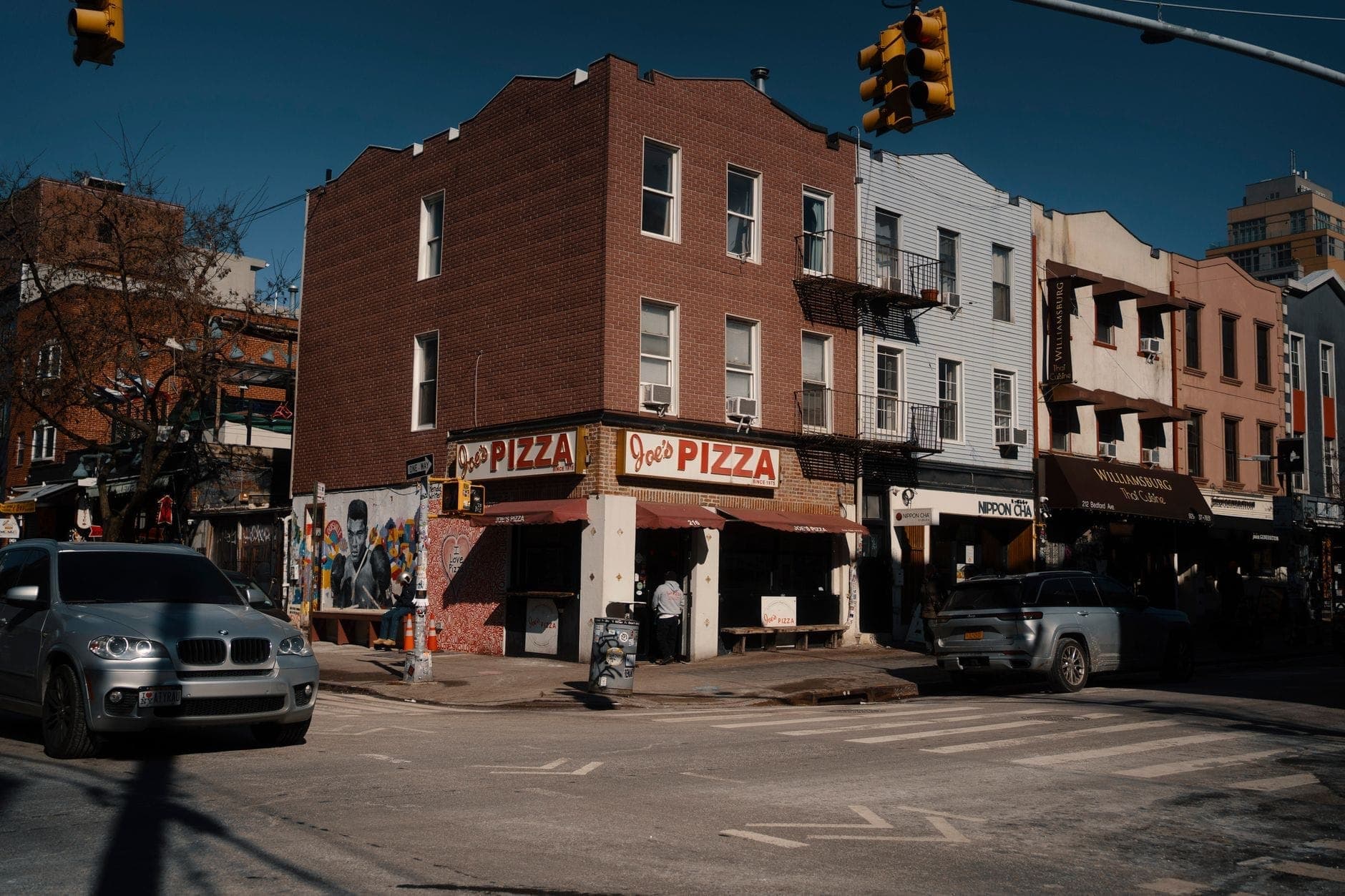 วิวถนนของร้าน Joe's Pizza อันโด่งดังใน West Village นครนิวยอร์ก พร้อมรถยนต์และผู้คนด้านนอกร้านพิซซ่า