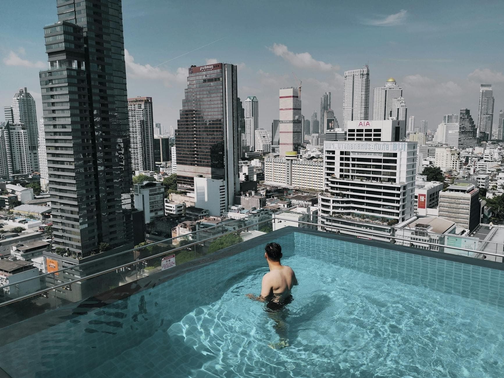 Piscina a sfioro sul tetto con vista sulla skyline di Bangkok, tipico soggiorno in hotel nei quartieri centrali.