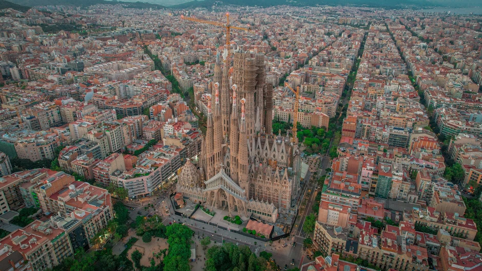 Aerial na tingin ng distrito ng Eixample sa Barcelona na nagtatampok ng iconic na Sagrada Familia na napapalibutan ng natatanging grid ng mga gusali at mga kalye na may punong-kahoy.