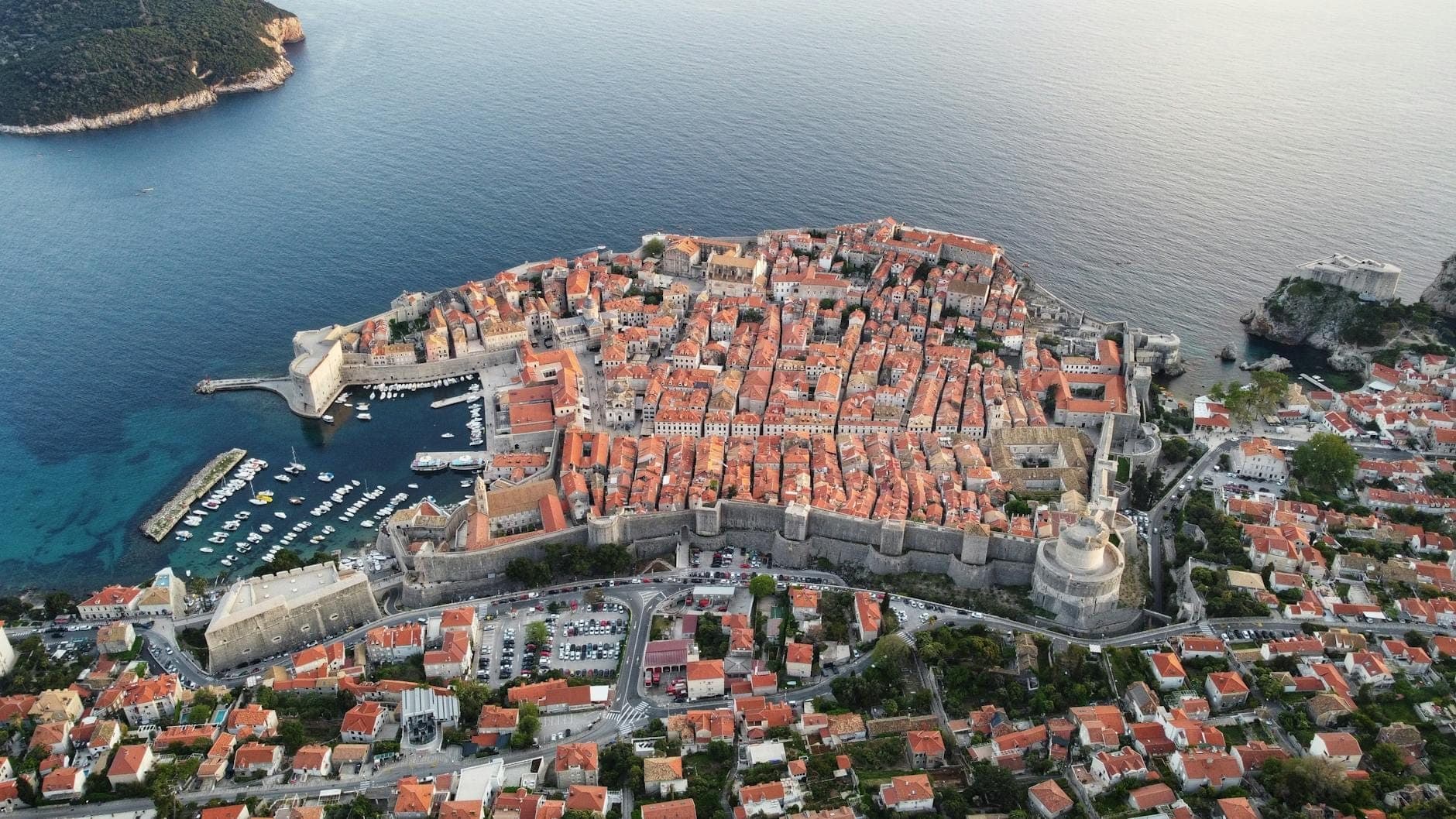 Pemandangan udara Dubrovnik yang menampilkan Kota Tua, tembok kota, kawasan sekitarnya, dan Laut Adriatik, menggambarkan berbagai area menginap bagi pengunjung.