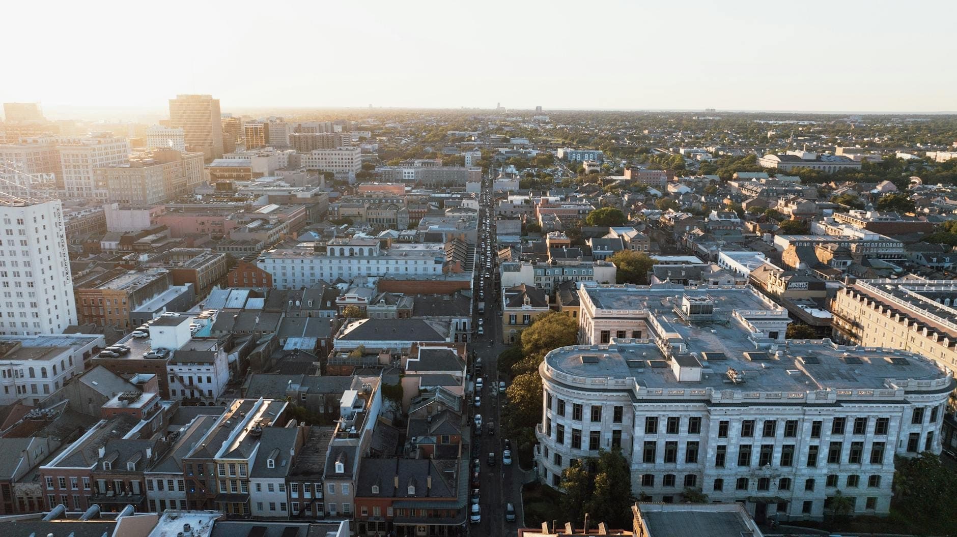 Vue aérienne de La Nouvelle-Orléans montrant un mélange de bâtiments historiques et de quartiers résidentiels au coucher du soleil.