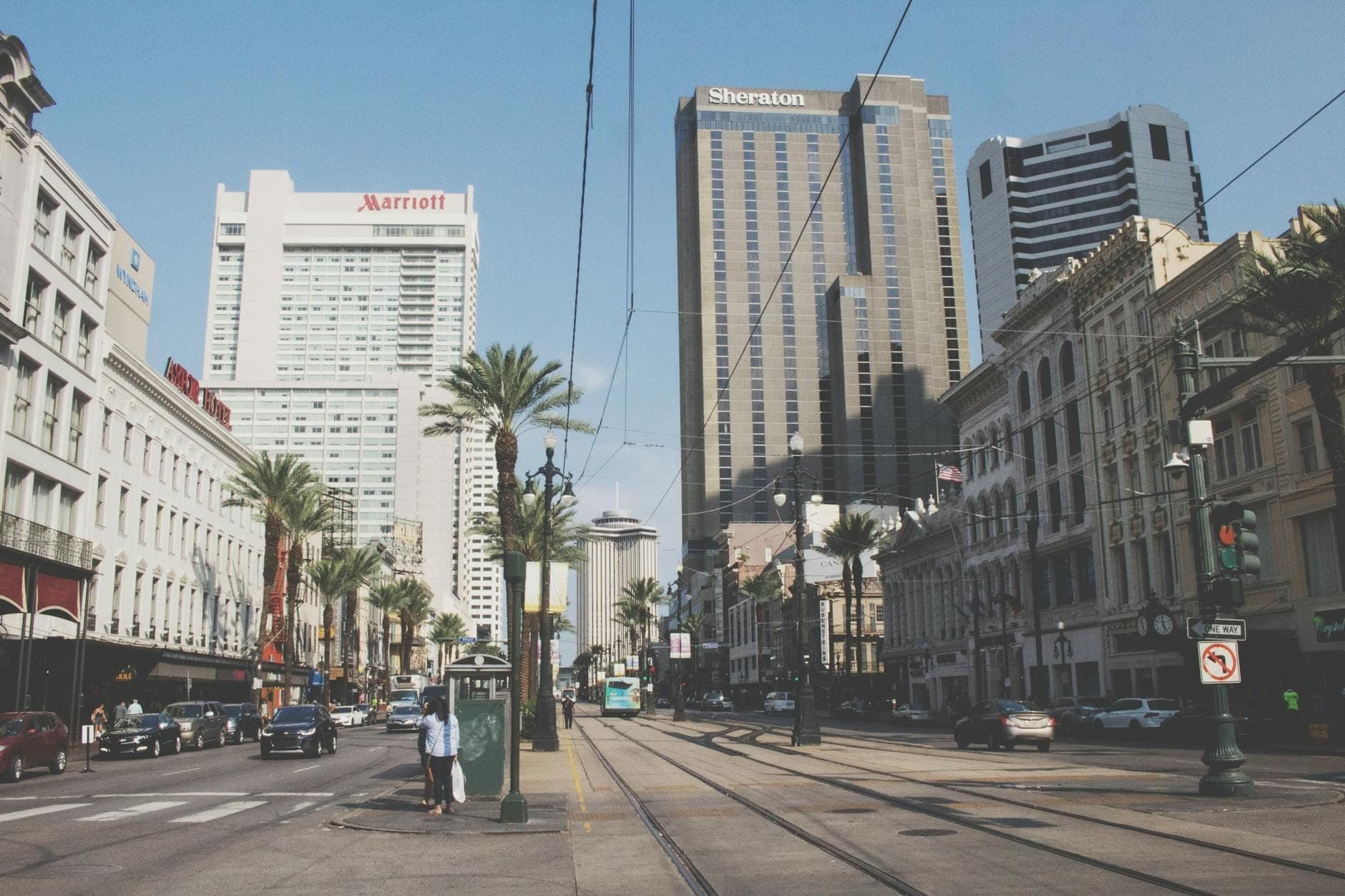 Vue au niveau de la rue du New Orleans Central Business District avec de grands hôtels, des palmiers, des rails de tramway et de grands immeubles des deux côtés.