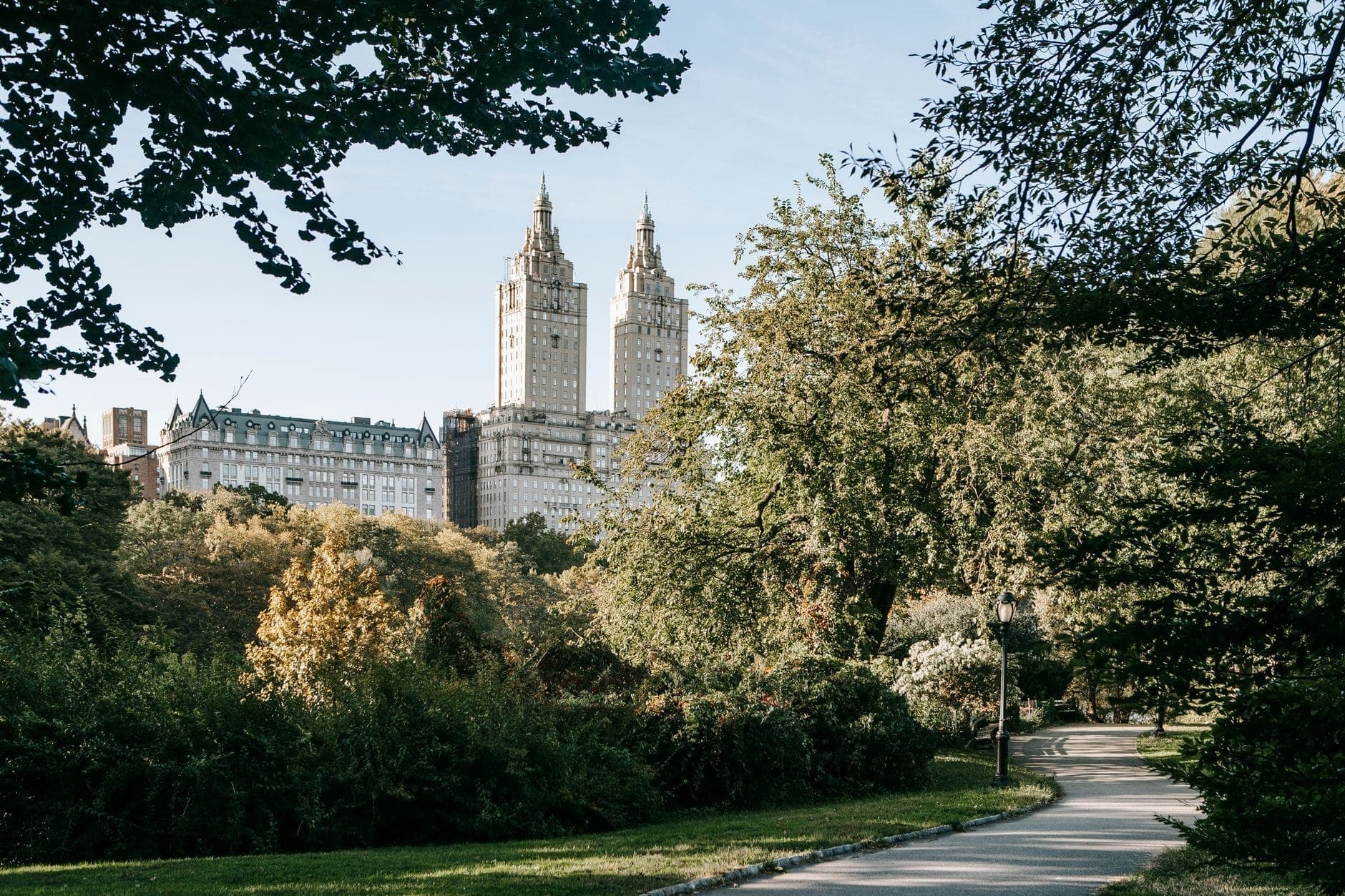 วิวอพาร์ตเมนต์สองหอคอยอันเป็นสัญลักษณ์ของ Upper West Side ที่สูงตระหง่านเหนือต้นไม้เขียวขจีใน Central Park ในวันที่แดดจ้า