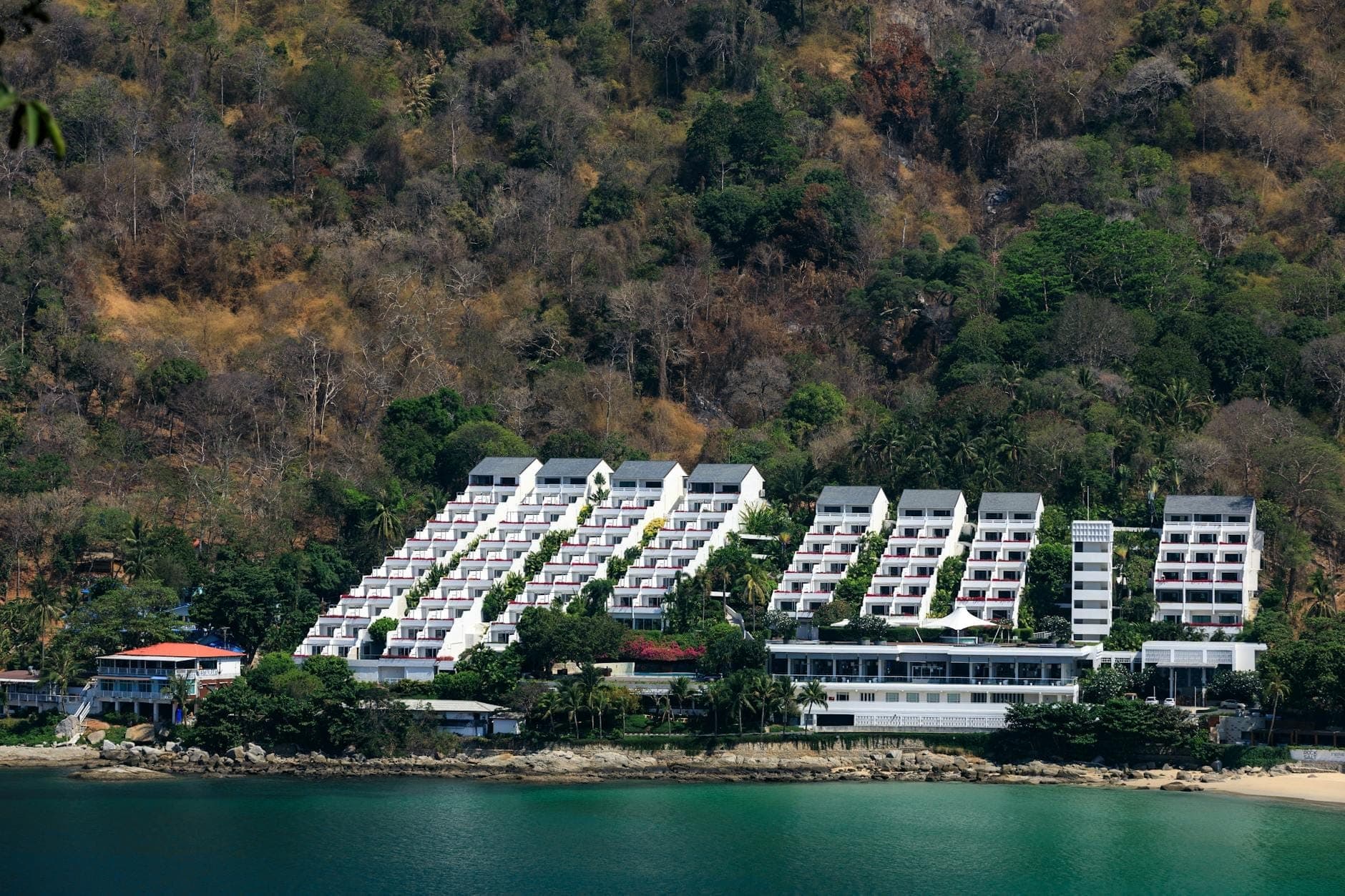 Magarang beachfront resort complex na nakatayo sa harap ng kagubatan sa burol ng Phuket, na napapalibutan ng turkesang tubig, na sumasalamin sa eksklusibong pakiramdam ng Kamala, Surin, at Bang Tao.
