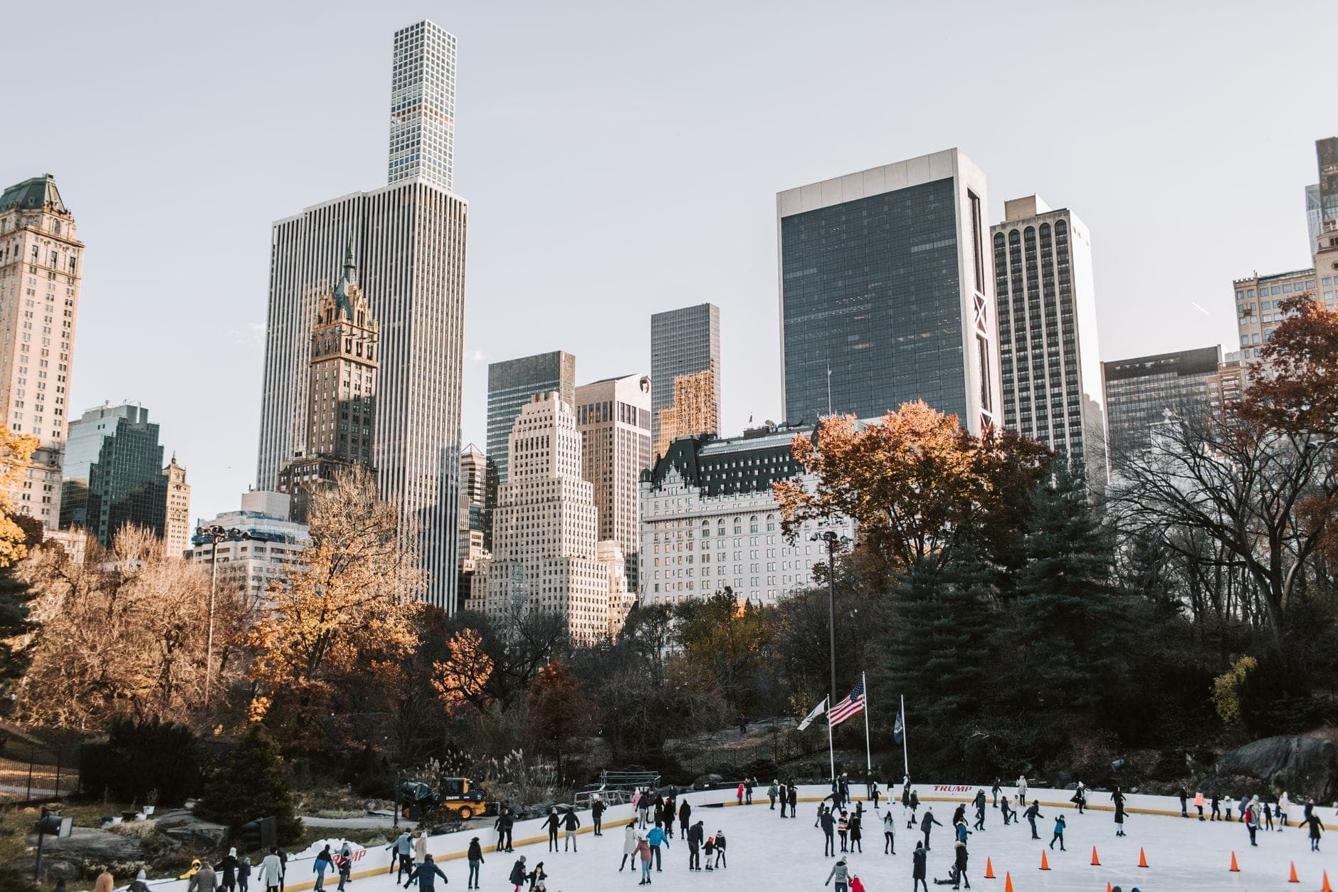ฝูงชนกำลังเล่นสเก็ตน้ำแข็งที่ Wollman Rink กลางเซ็นทรัลพาร์ค ฉากหลังเป็นตึกสูงแมนฮัตตันในวันที่อากาศแจ่มใสช่วงฤดูใบไม้ร่วงหรือฤดูหนาว