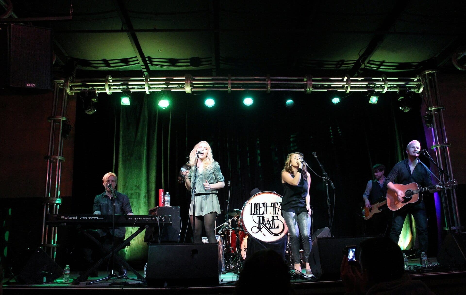 Live band performing under green stage lights at 3rd & Lindsley, Nashville, with keyboard, drums, guitar, and two vocalists on stage.