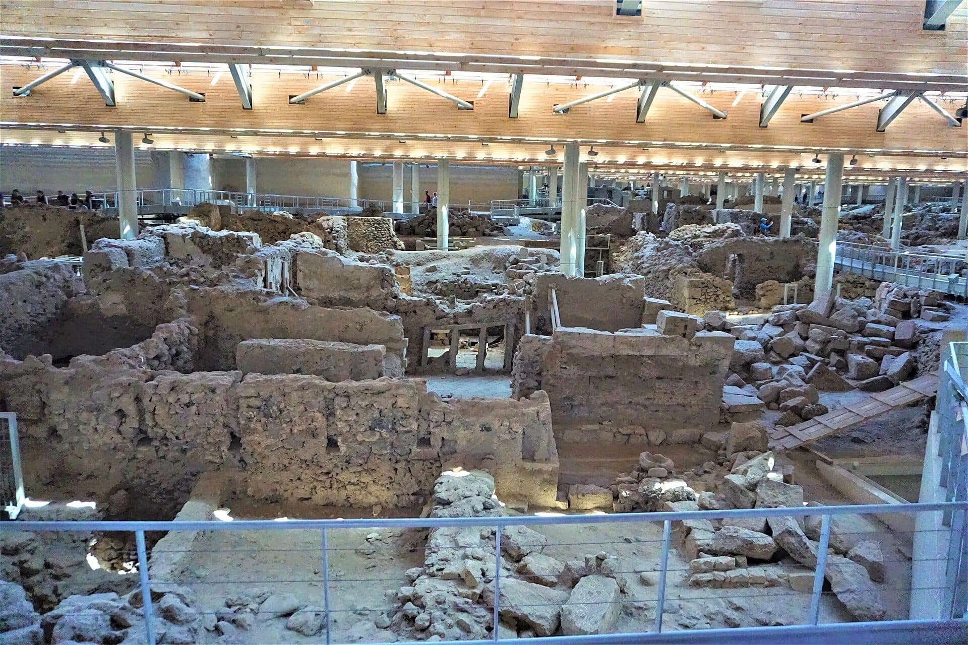 Überblick über die archäologische Stätte Akrotiri mit antiken Steinruinen, Gehwegen und einem modernen schützenden Holzdach in Santorini.