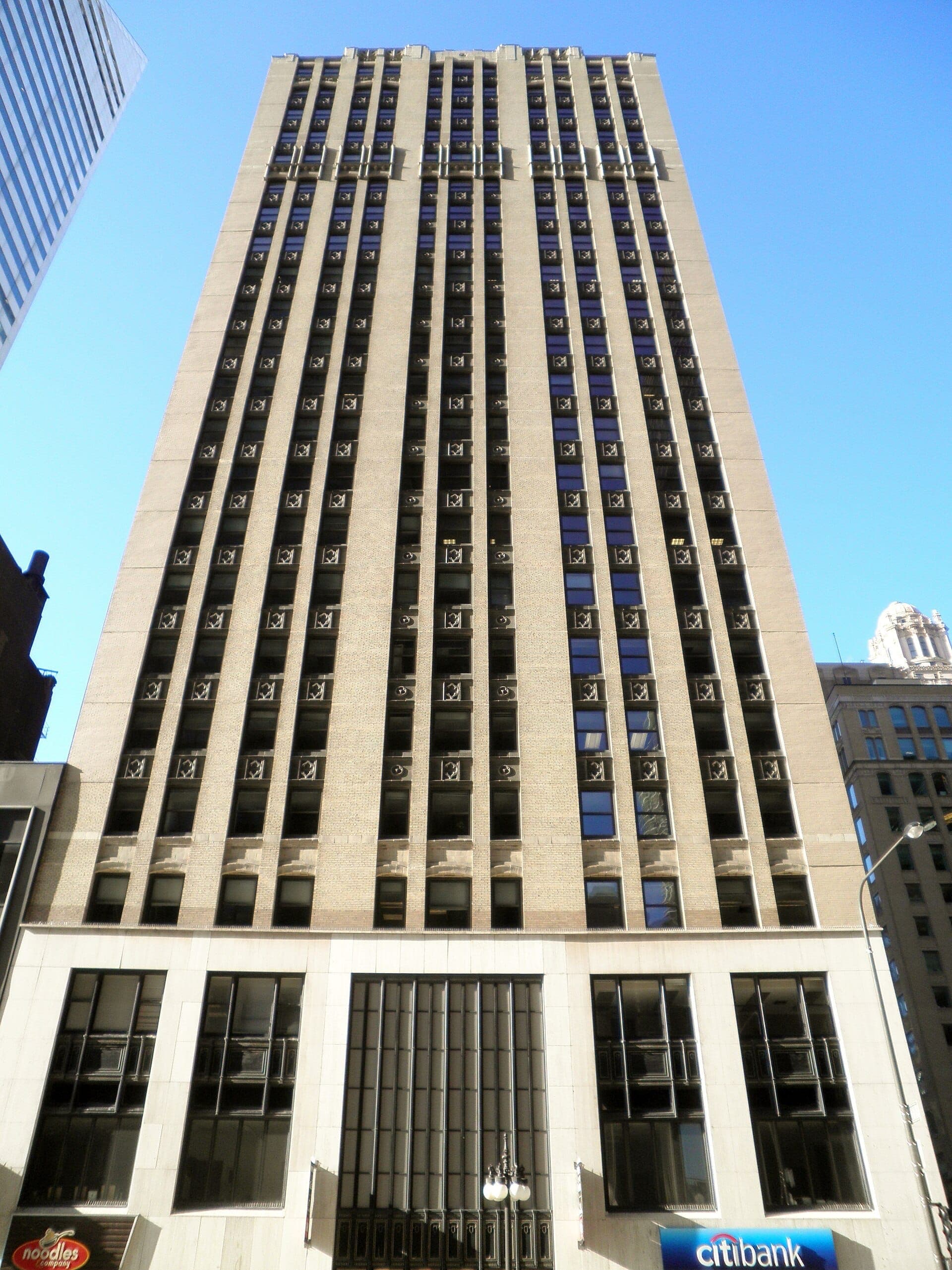 ตึกระฟ้าสีเบจสูงที่ 180 N. Michigan Avenue ซึ่งเป็นที่ตั้งของ American Writers Museum มีหน้าต่างสมมาตรโดดเด่นบนท้องฟ้าสีฟ้าใสของ Chicago.