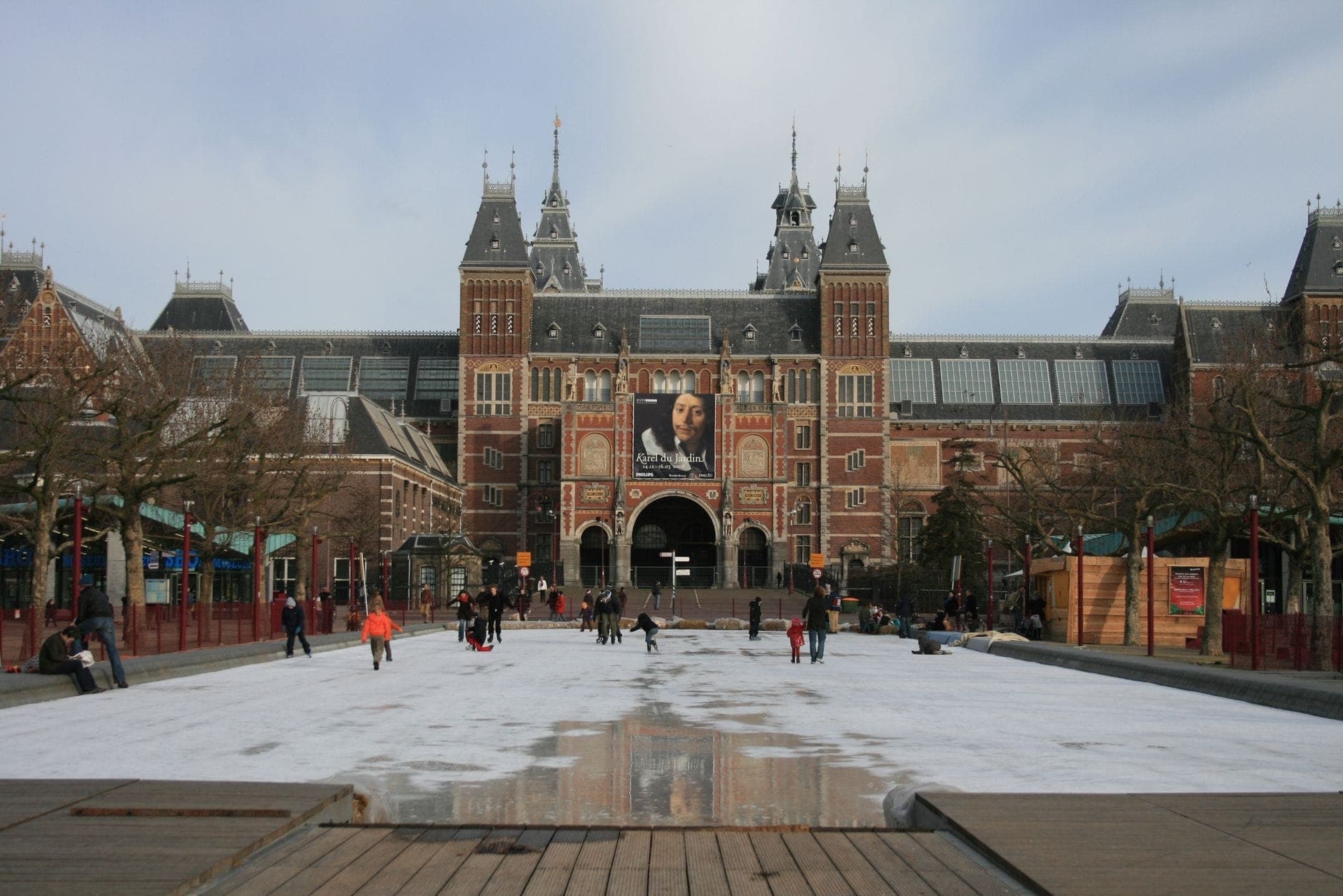 Menschen beim Schlittschuhlaufen auf der Eisbahn am Museumplein vor dem Rijksmuseum in Amsterdam im Winter.