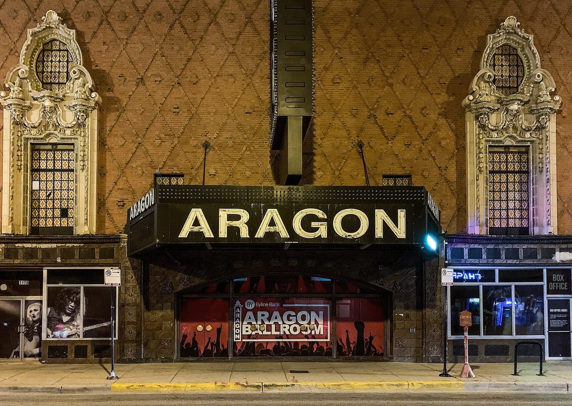 ด้านหน้าของ Aragon Ballroom ในชิคาโก โชว์หน้าต่างประดับประดา ลวดลายอิฐ และป้ายมาร์คีขนาดใหญ่ในยามค่ำคืน