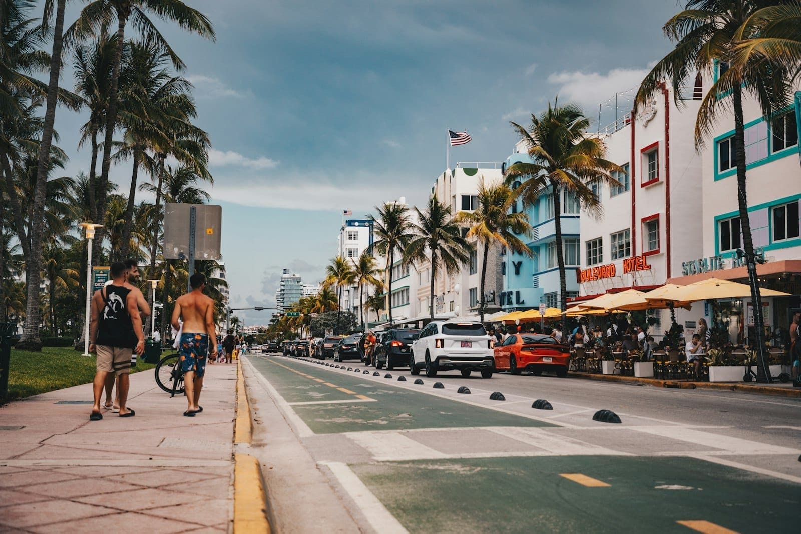 Vue sur Ocean Drive à Miami Beach avec des hôtels art déco, des palmiers, des cafés en terrasse, des piétons et une lumière d'après-midi envoûtante.