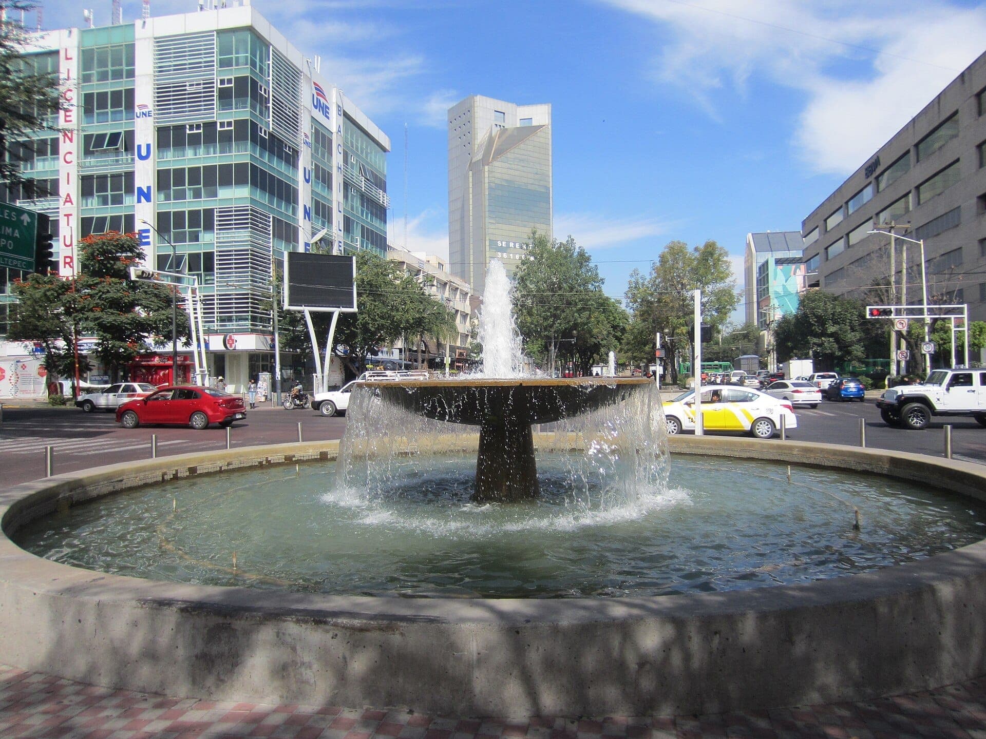 น้ำพุที่มีน้ำไหลเป็นชั้นๆ ใจกลาง Avenida Chapultepec ล้อมรอบด้วยอาคารสำนักงานสมัยใหม่และการจราจรในเมือง Guadalajara