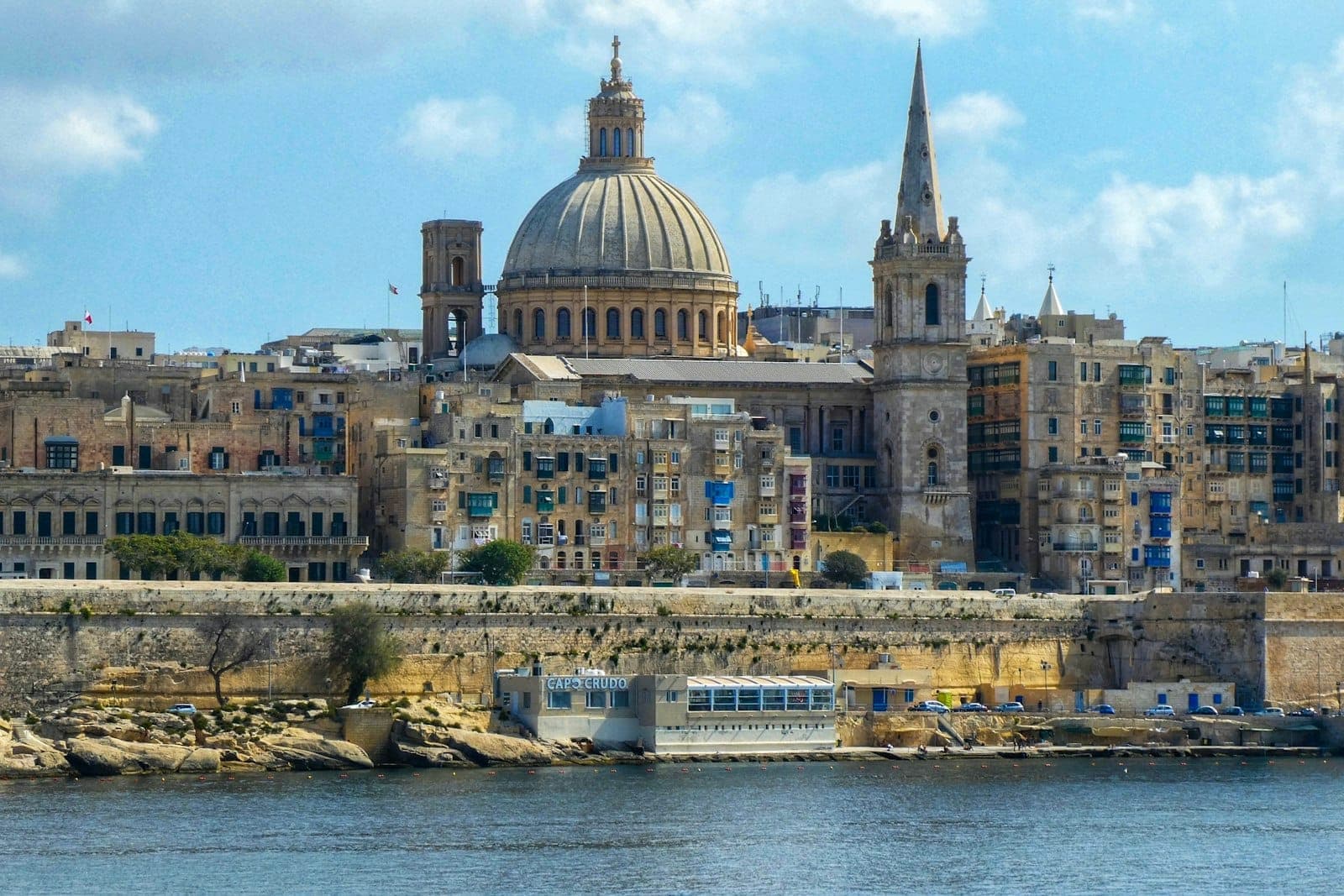 Panoramablick auf die Skyline von Valletta mit der markanten ovalen Kuppel der Basilika Unserer Lieben Frau vom Berge Karmel, die sich über die historischen Kalksteingebäude erhebt.