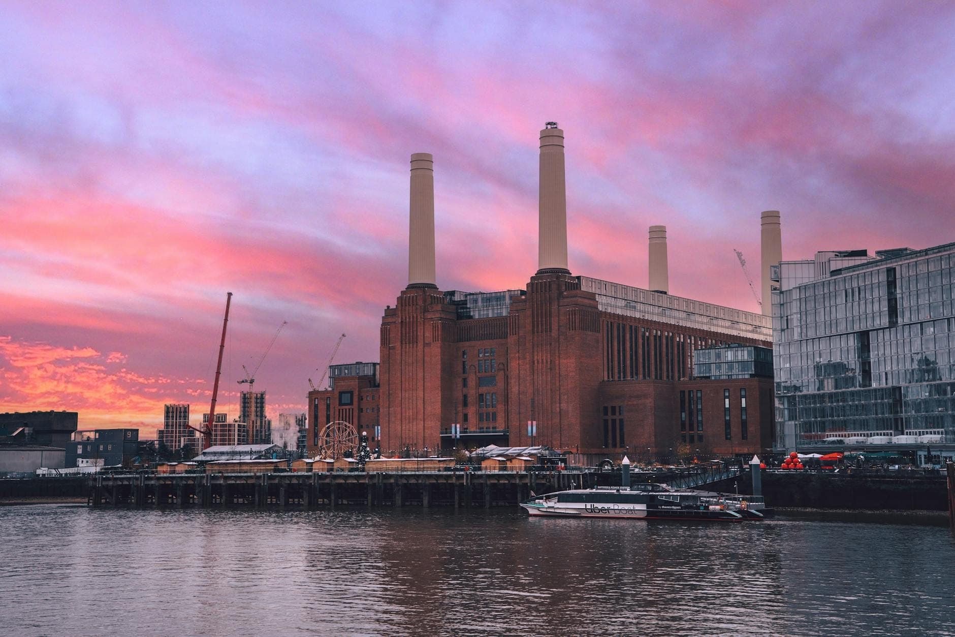 Battersea Power Station con sus icónicas chimeneas vista desde el otro lado del Támesis bajo un vibrante cielo de atardecer rosa y morado.