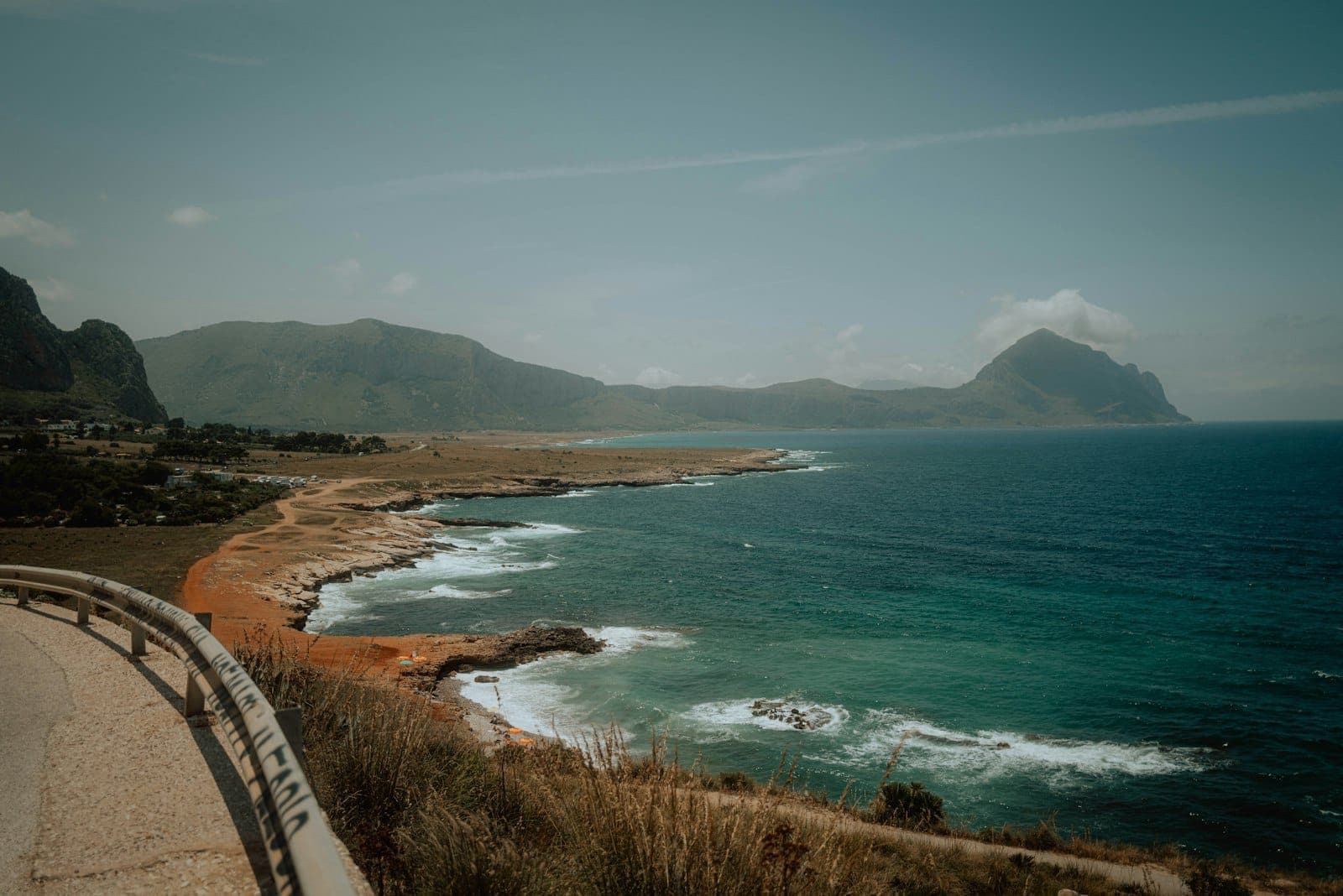 Paikot na daan sa tabing-dagat sa itaas ng turquoise na dagat, na may mga dramatikong bundok na limestone at magaspang na baybayin na katangian ng hilagang baybayin ng Tyrrhenian sa Sicily.