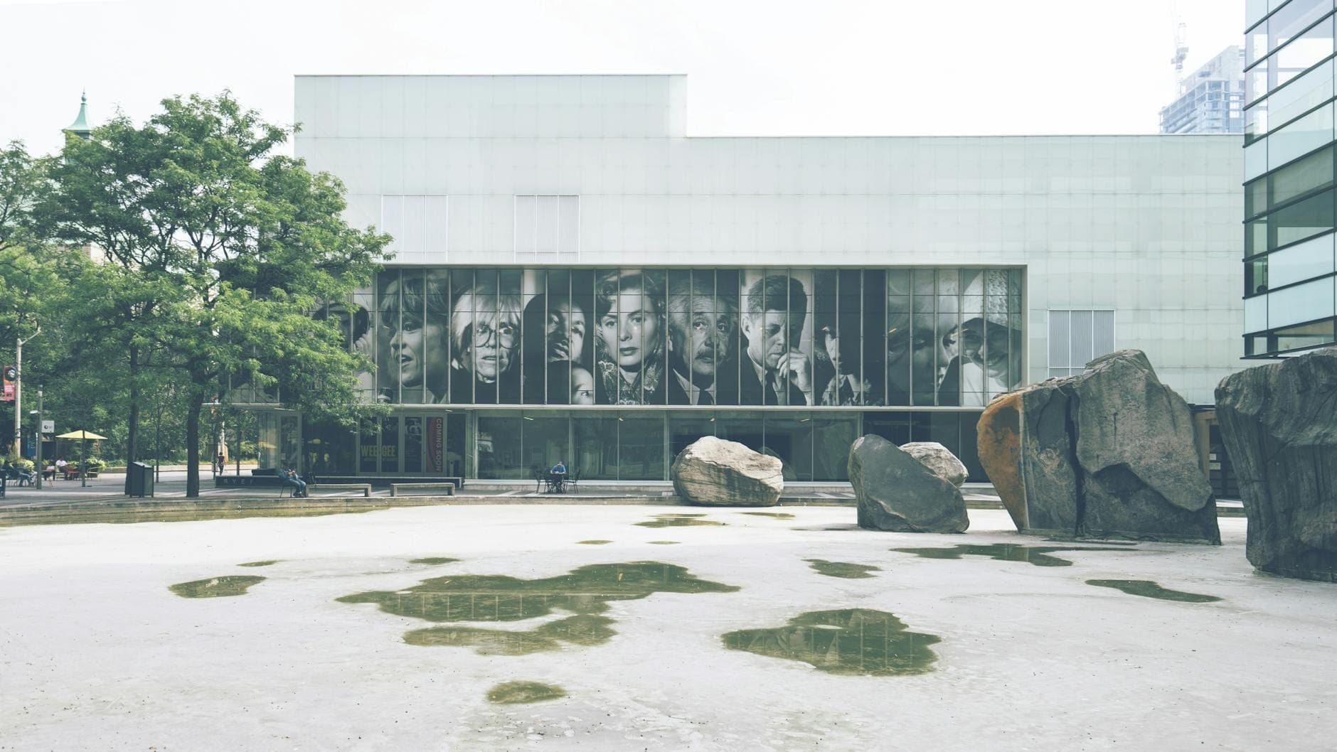 Edificio del museo de arte moderno en Chicago con grandes retratos en las ventanas y rocas en la plaza de esculturas frente al edificio.
