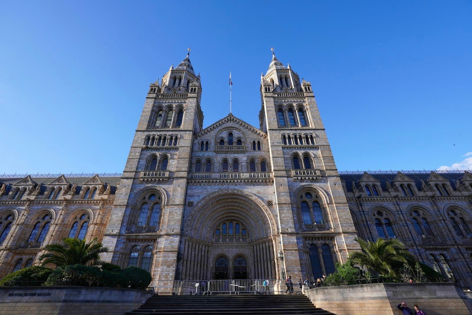 Große Fassade des Natural History Museum in South Kensington, London, unter einem blauen Himmel mit zwei hohen Türmen.
