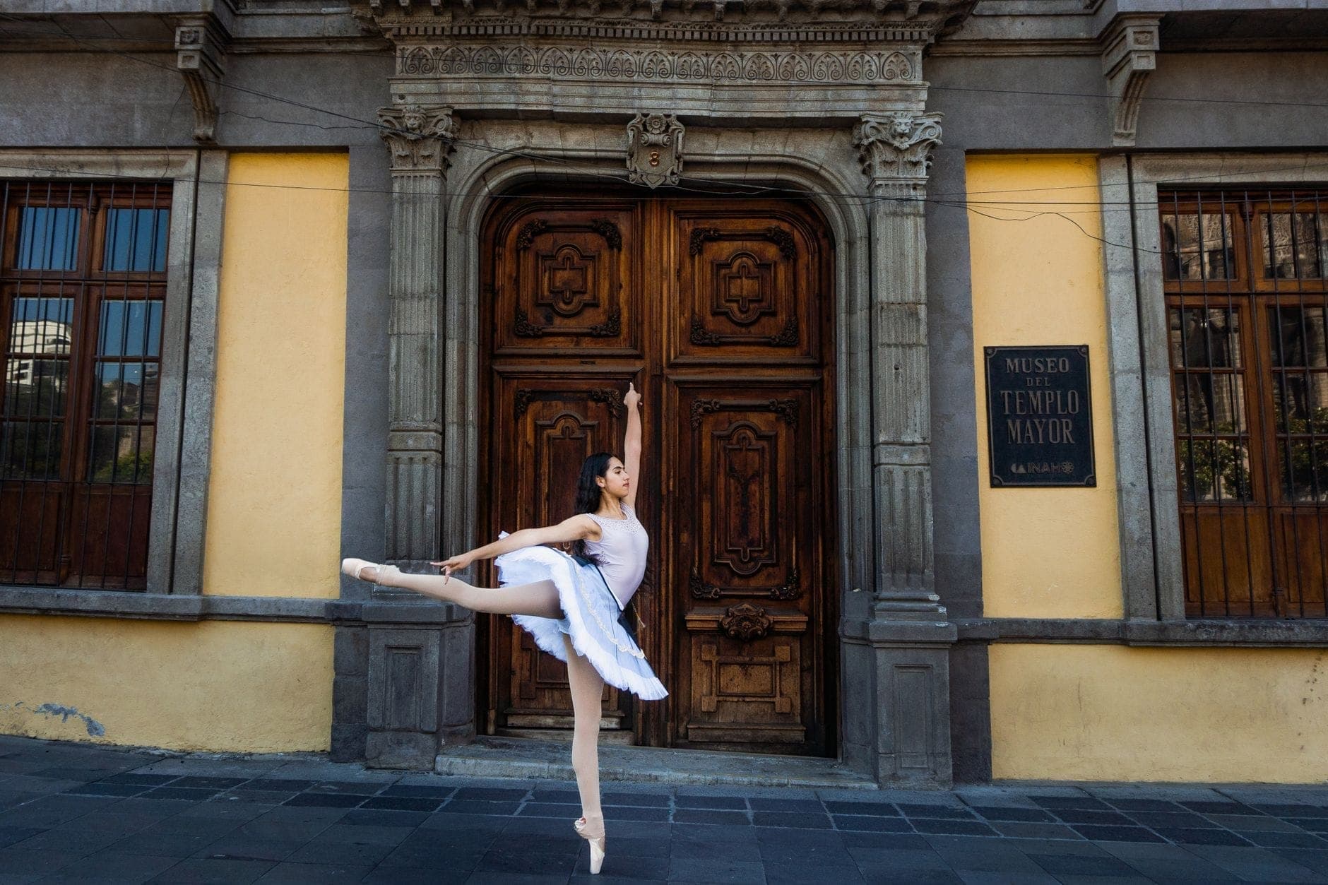A ballerina poses in front of the entrance to Museo del Templo Mayor in Mexico City, an important archaeological museum.