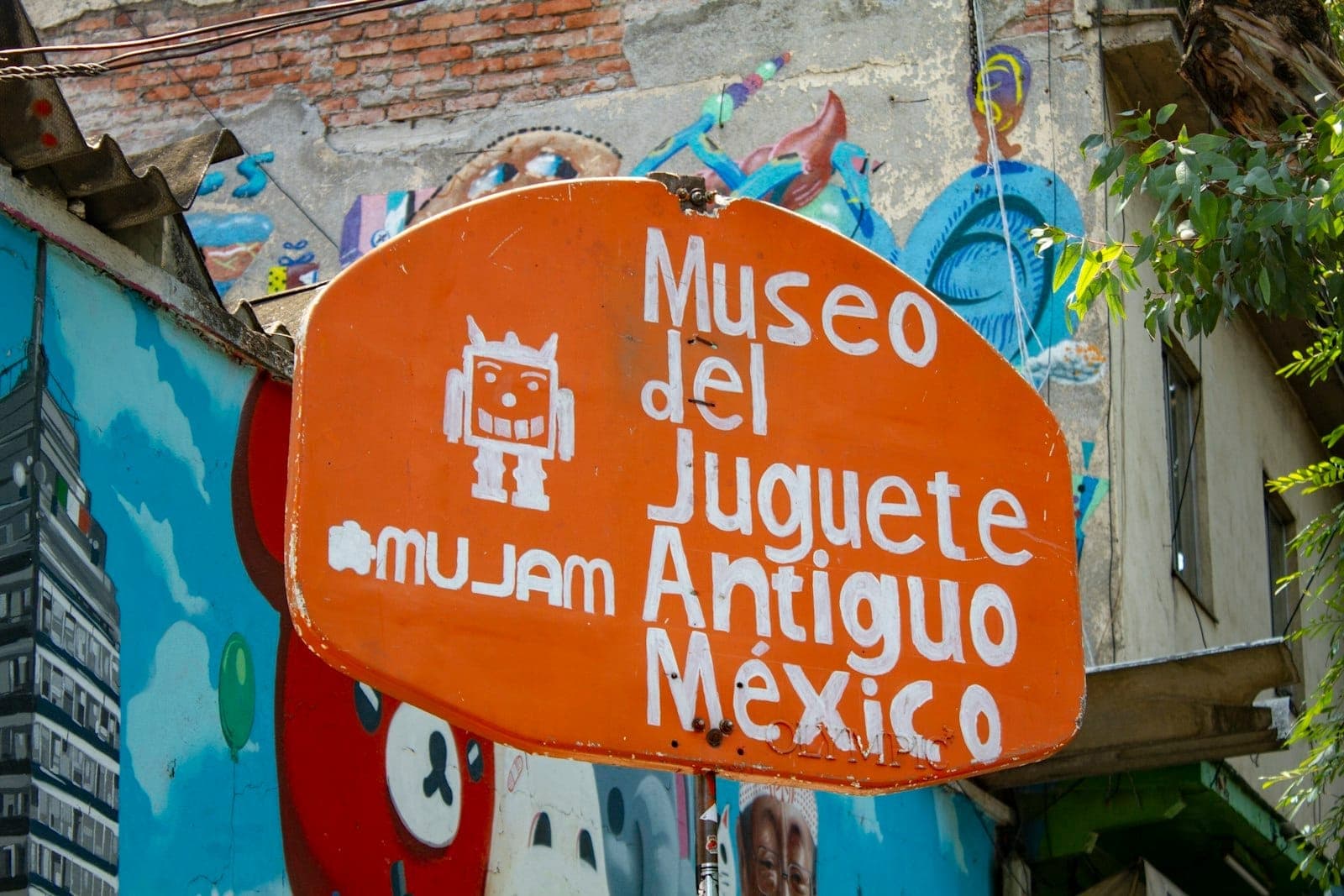Sign for Museo del Juguete Antiguo México, surrounded by colorful urban murals.