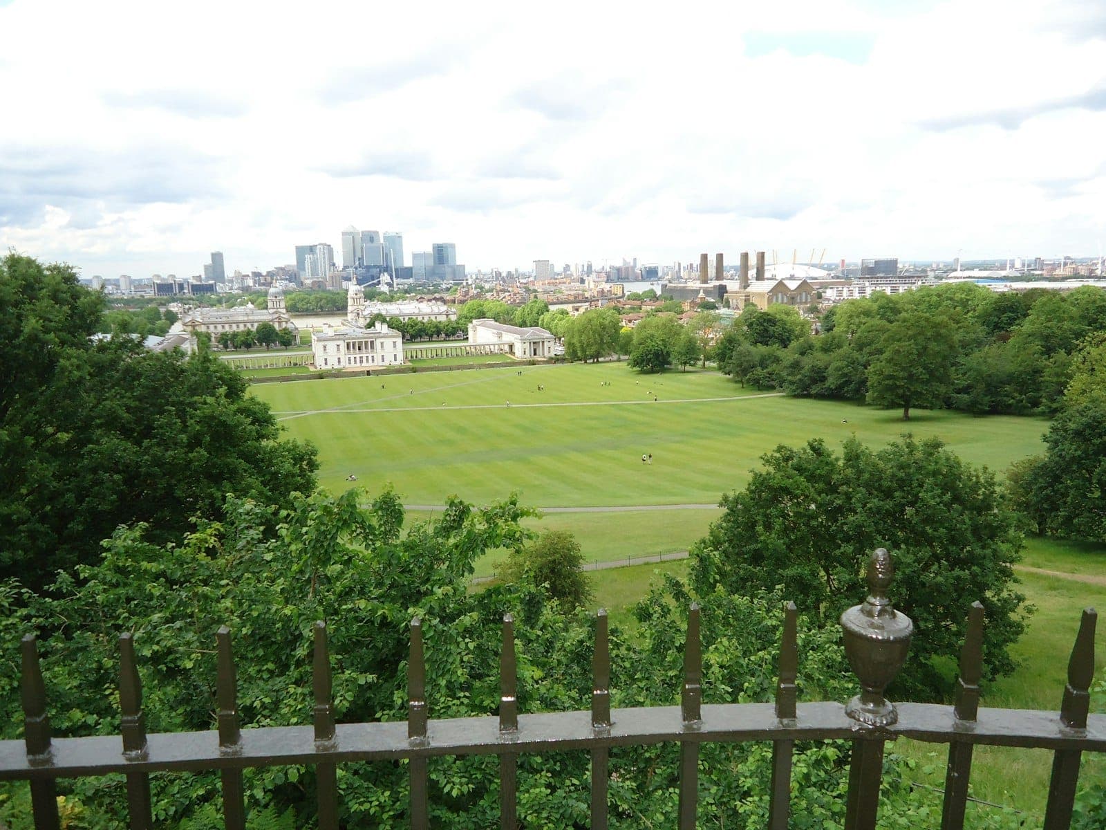 Blick vom Greenwich Park mit dem Royal Naval College und der Londoner Skyline in der Ferne an einem bewölkten Tag