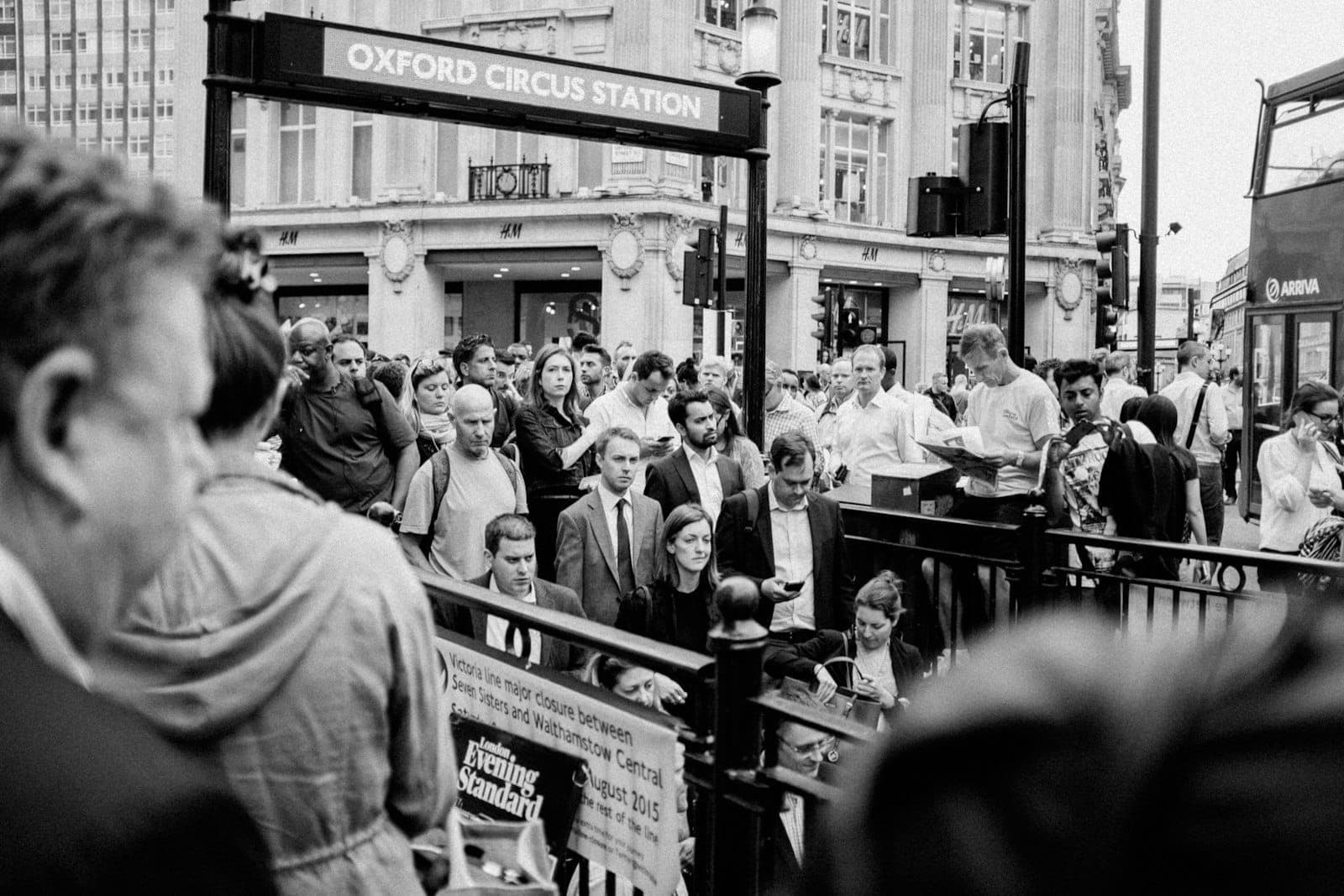 Folle di persone che escono dalla stazione Oxford Circus a Londra durante un momento di grande affluenza, illustrando il picco di affollamento e la congestione.