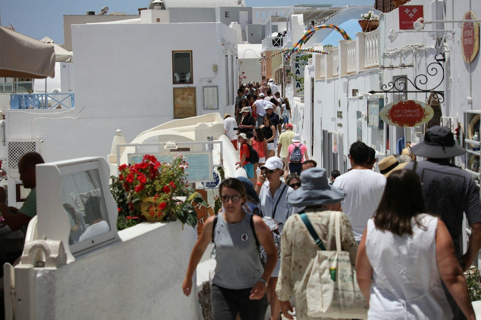 Multidões de pessoas caminhando pelas estreitas ruas caiadas de Santorini em um dia ensolarado
