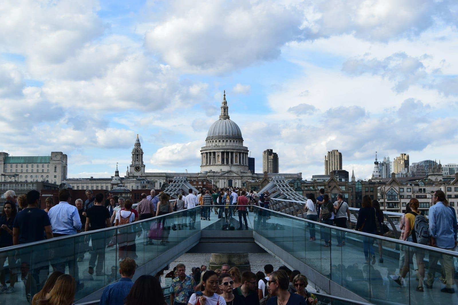 Folle che attraversano il Millennium Bridge verso la Cattedrale di St Paul's sotto un cielo luminoso e parzialmente nuvoloso nel centro di Londra