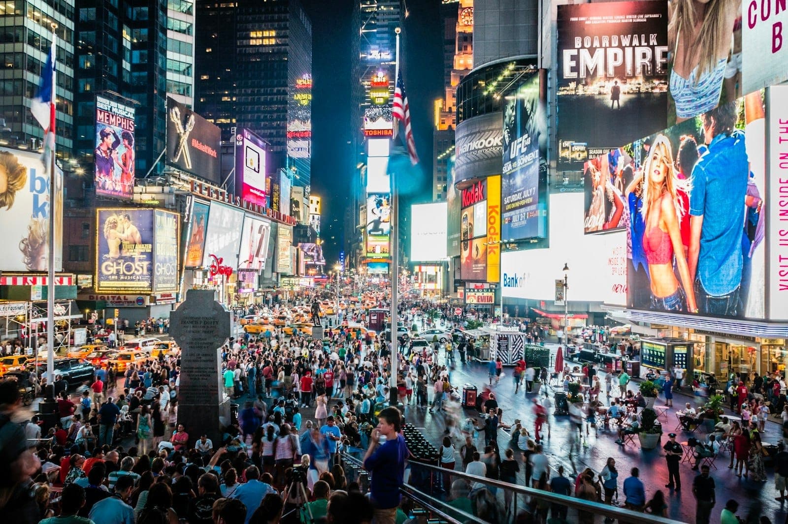 Times Square ที่คึกคักเต็มไปด้วยฝูงชน แสงไฟสว่างไสว และแท็กซี่ใน Midtown Manhattan ยามค่ำคืน