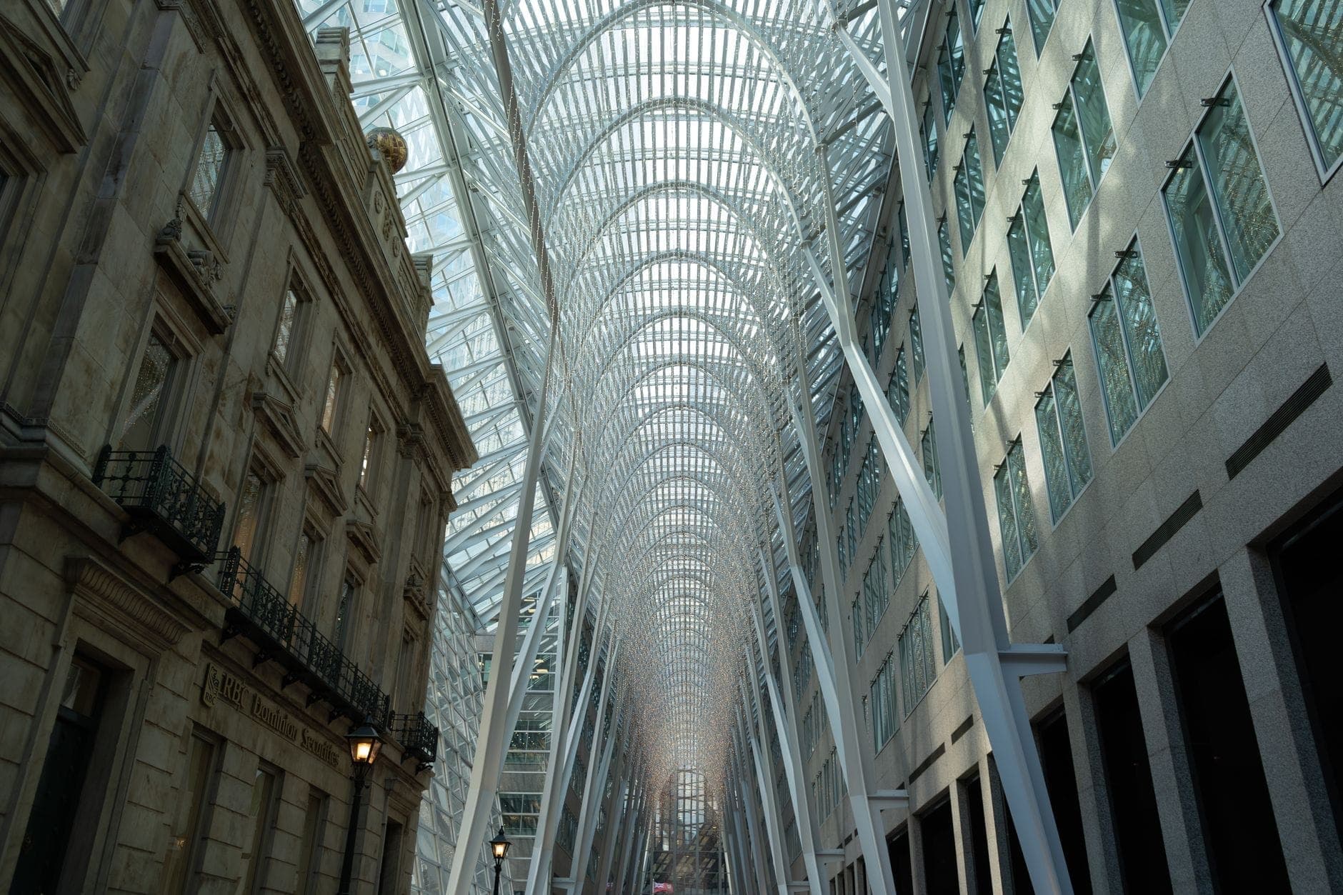 Vista panoramica della spettacolare volta in acciaio e vetro della Allen Lambert Galleria, fiancheggiata da edifici in pietra e vetro all'interno di Brookfield Place, Toronto.