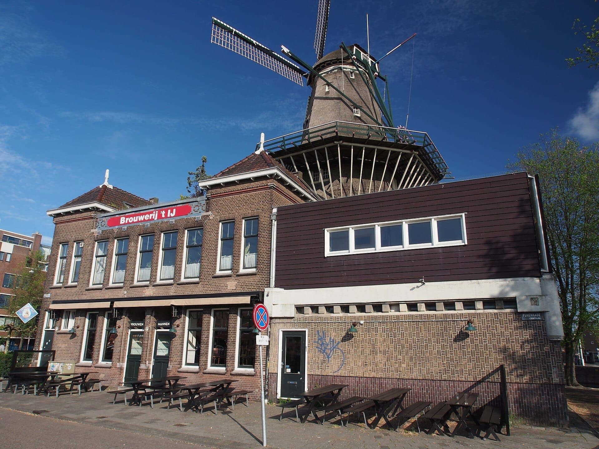 Außenansicht der Brauerei Brouwerij 't IJ und des Verkostungsraums mit Bänken im Freien, unterhalb der historischen Windmühle De Gooyer in Amsterdam.