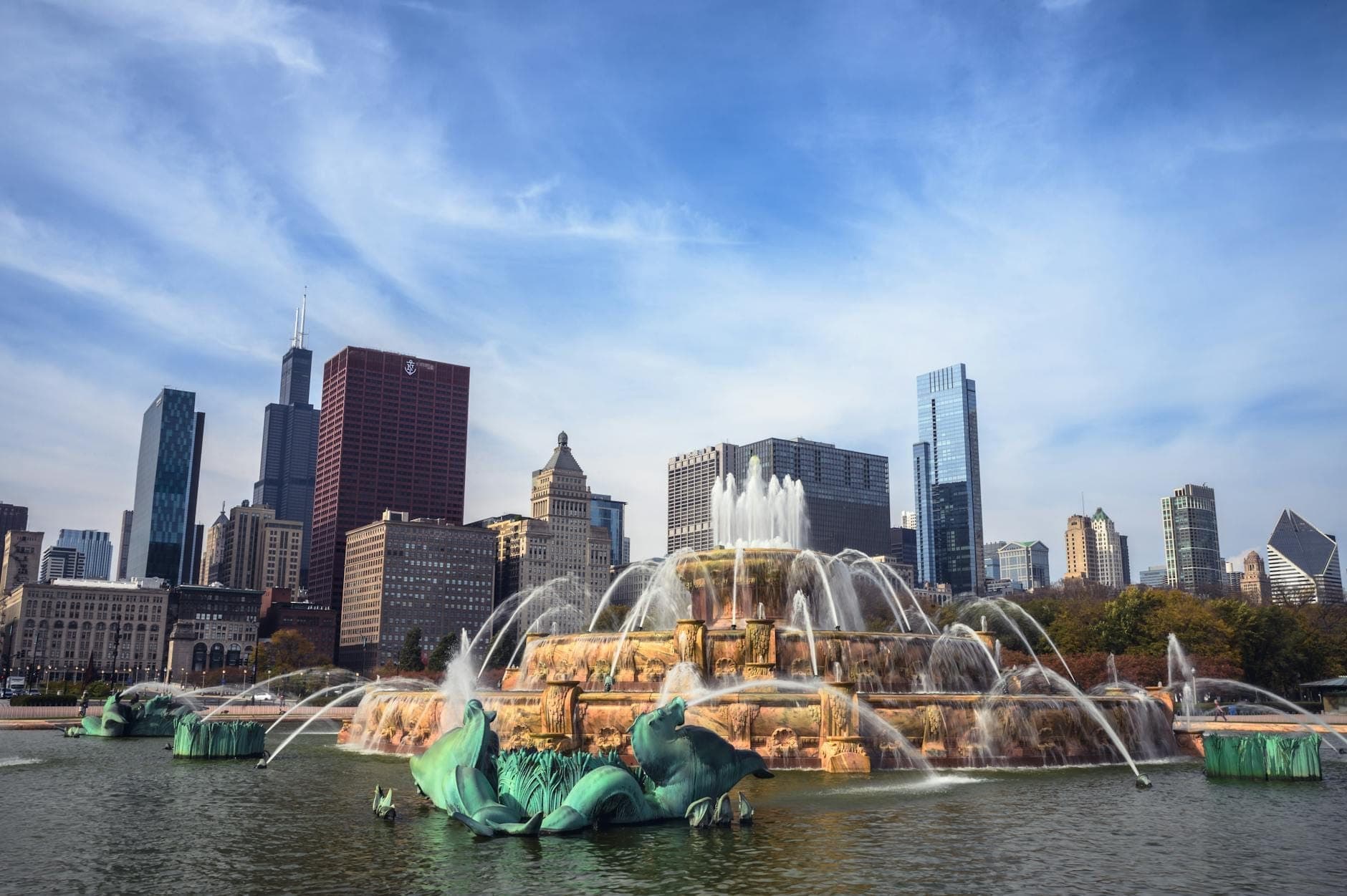 Buckingham Fountain sending streams of water high into the air, framed by Chicago’s skyline under a blue sky in Grant Park.