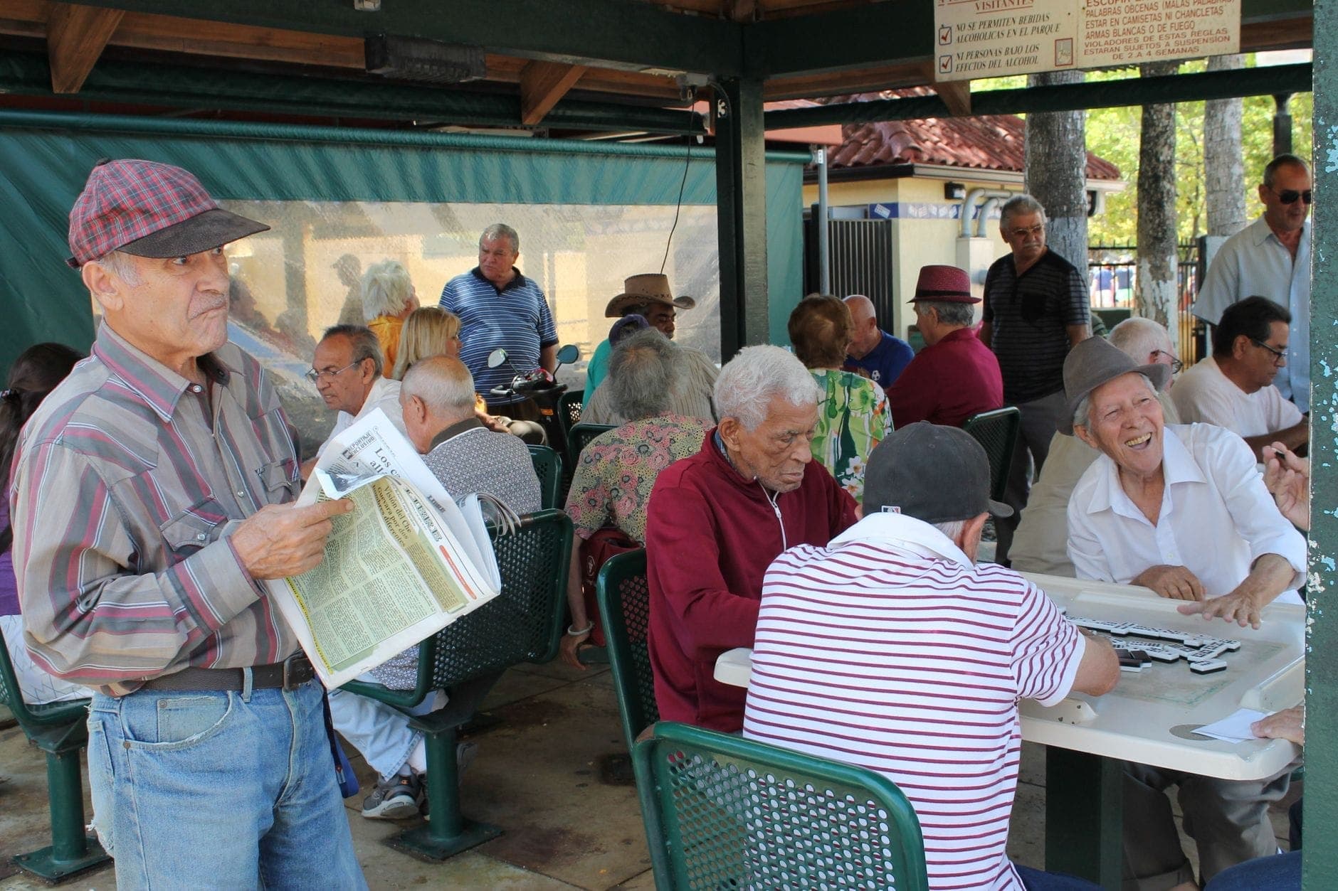 A group of older men socializing and playing dominoes in a shaded outdoor area, typical of Little Havana’s Domino Park in Miami.
