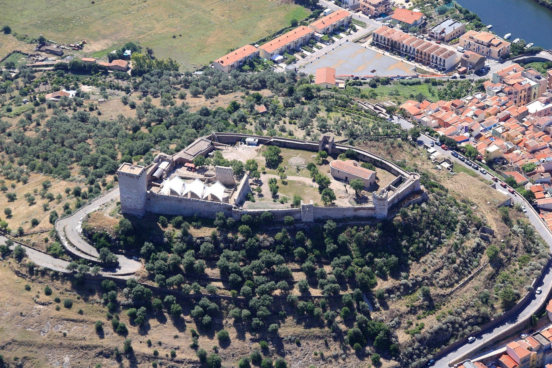 Vista aérea del Castello Malaspina, una fortaleza medieval en lo alto de la colina de Serravalle, rodeada de paisaje verde y con vistas a la colorida ciudad de Bosa.