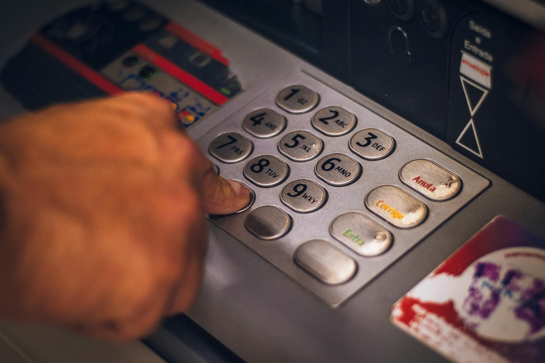 Eine Hand drückt Tasten auf einem Geldautomaten – Bargeld und Kartenzugang in Thailand im Fokus.